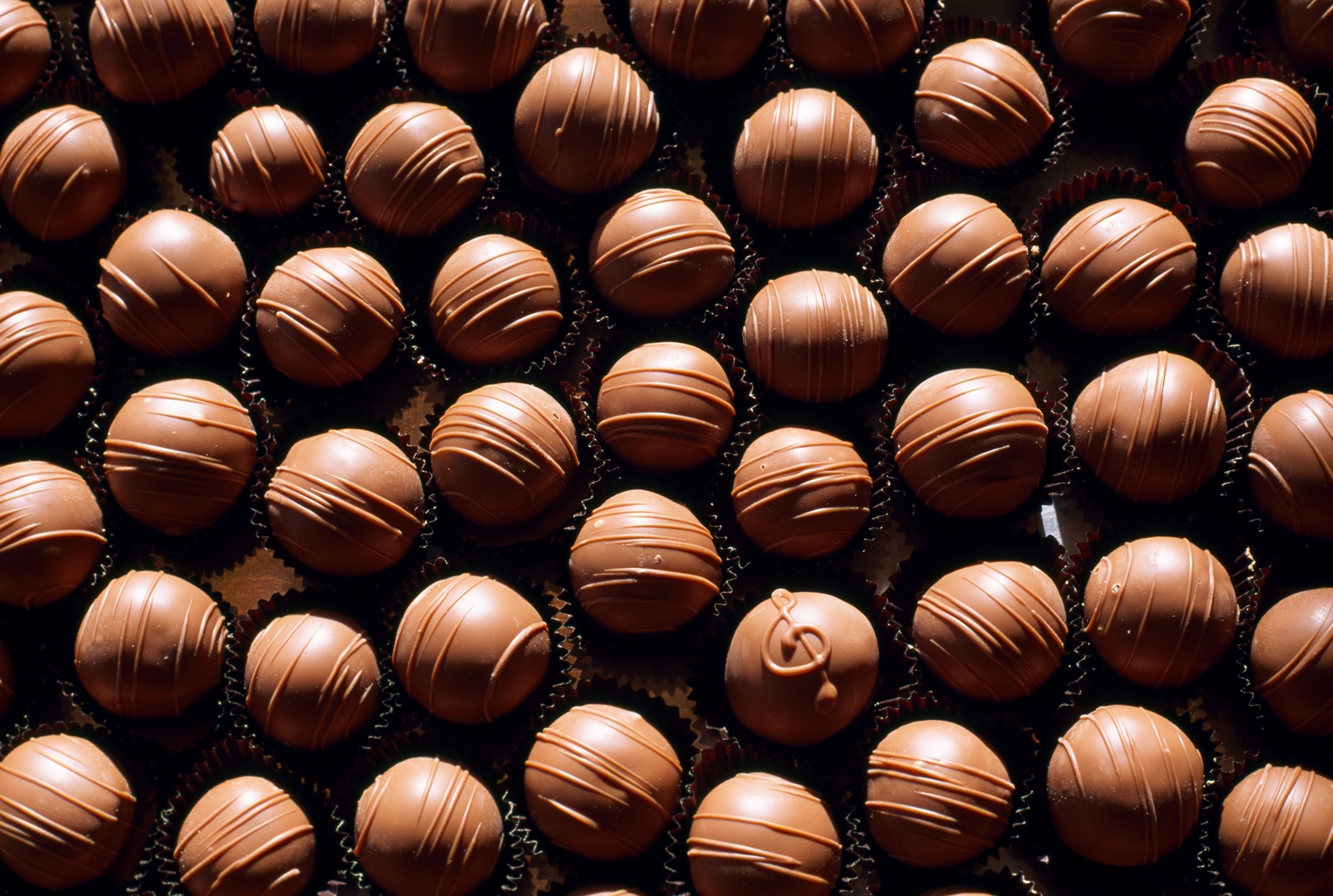 A large group of chocolates which all look the same except for one.