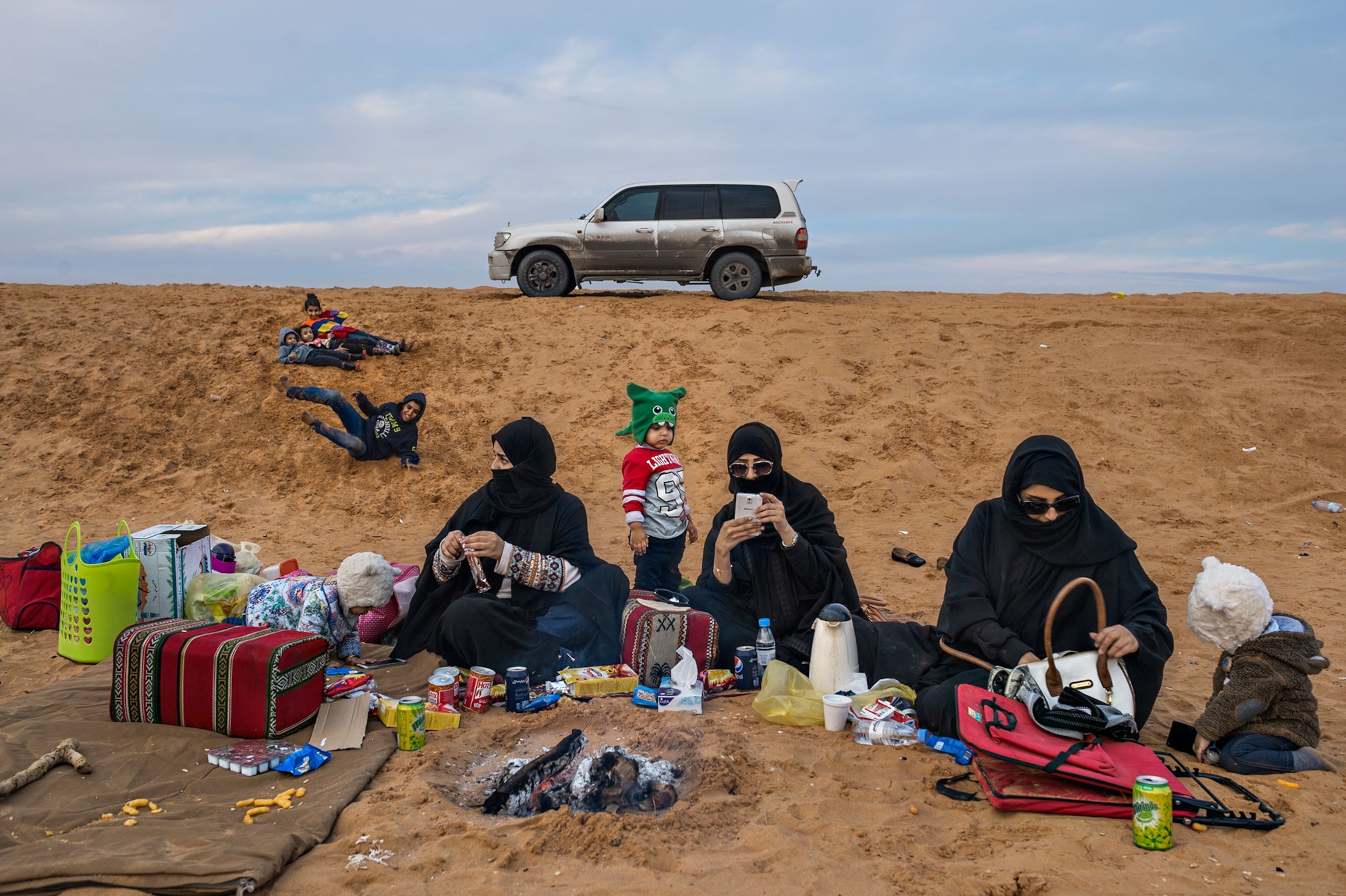 Sisters relax as their children play on the slopes of the desert outside Riyadh in Saudi Arabia.