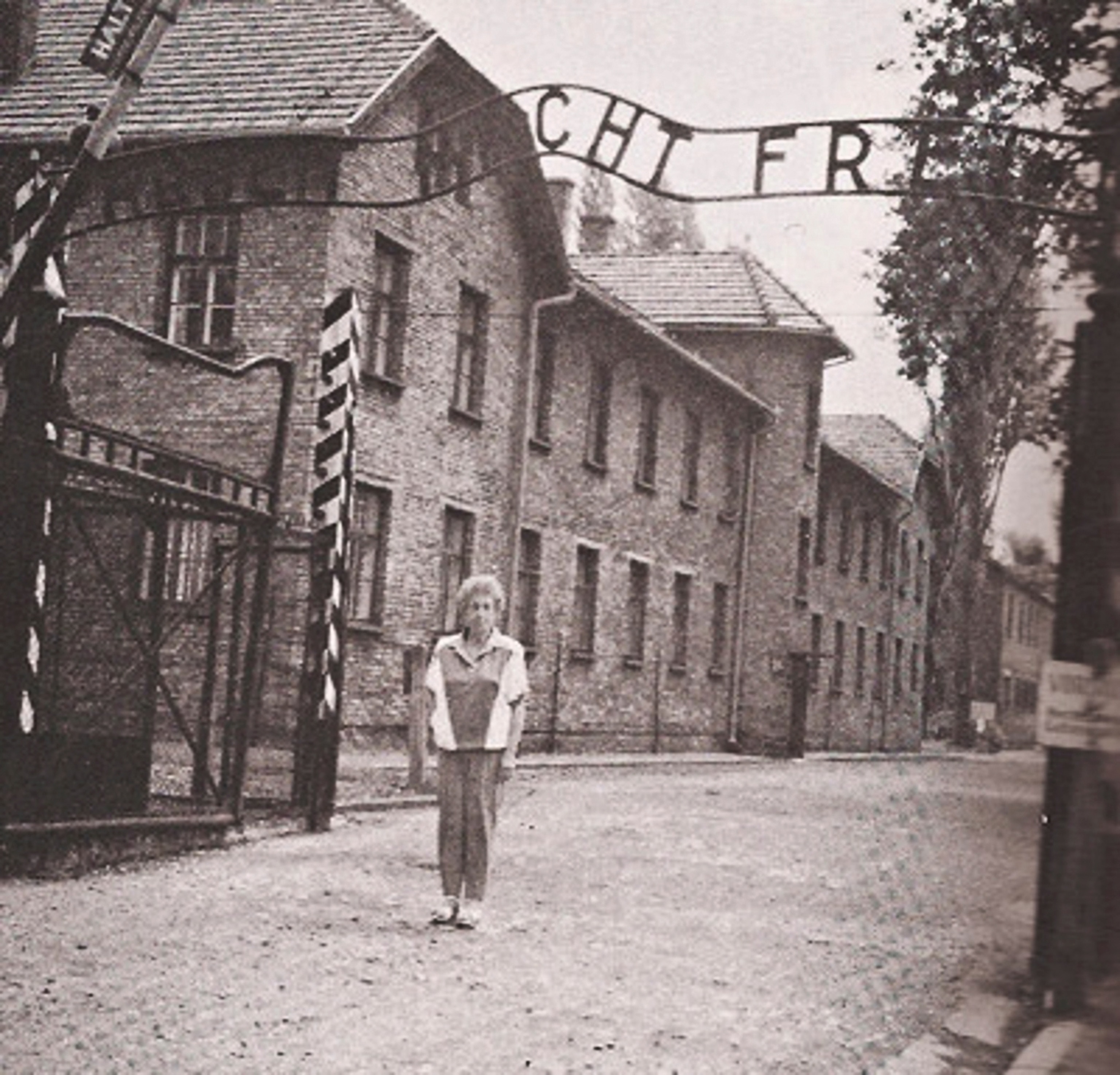 Rena as an adult in front of Auschwitz