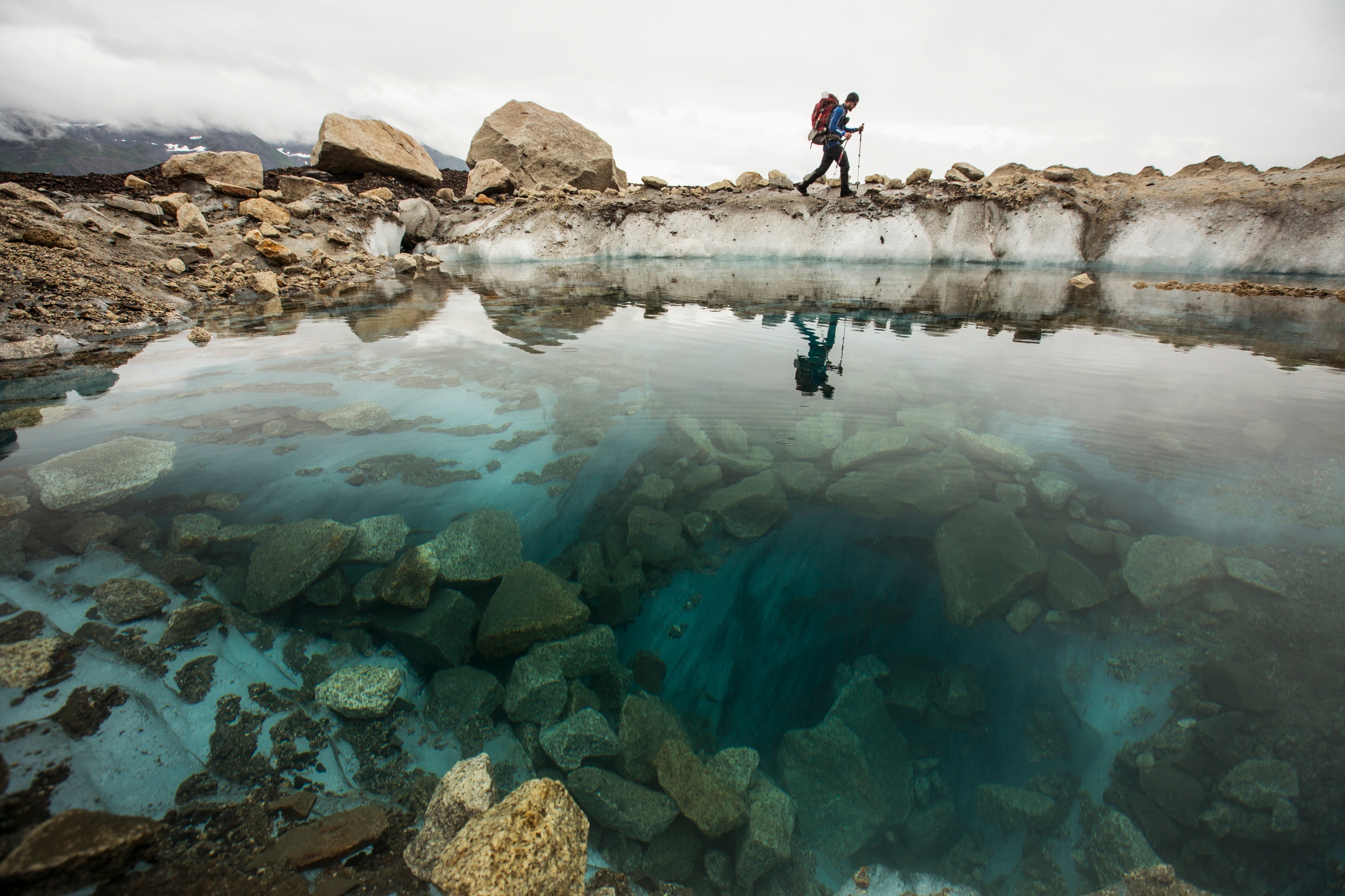A hiker walks past a glacial pool in Denali National Park