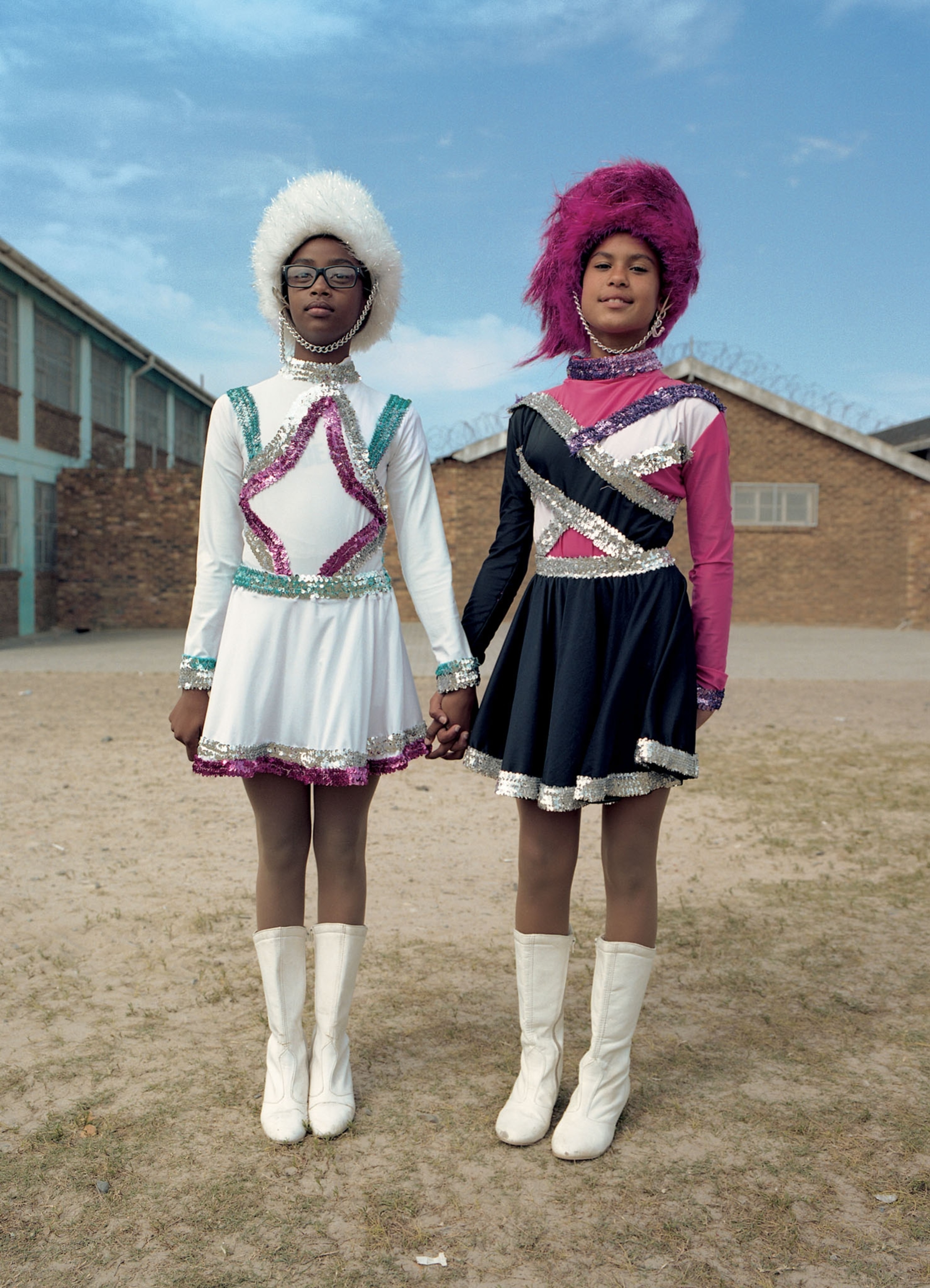two young women holding hands in colorful uniforms