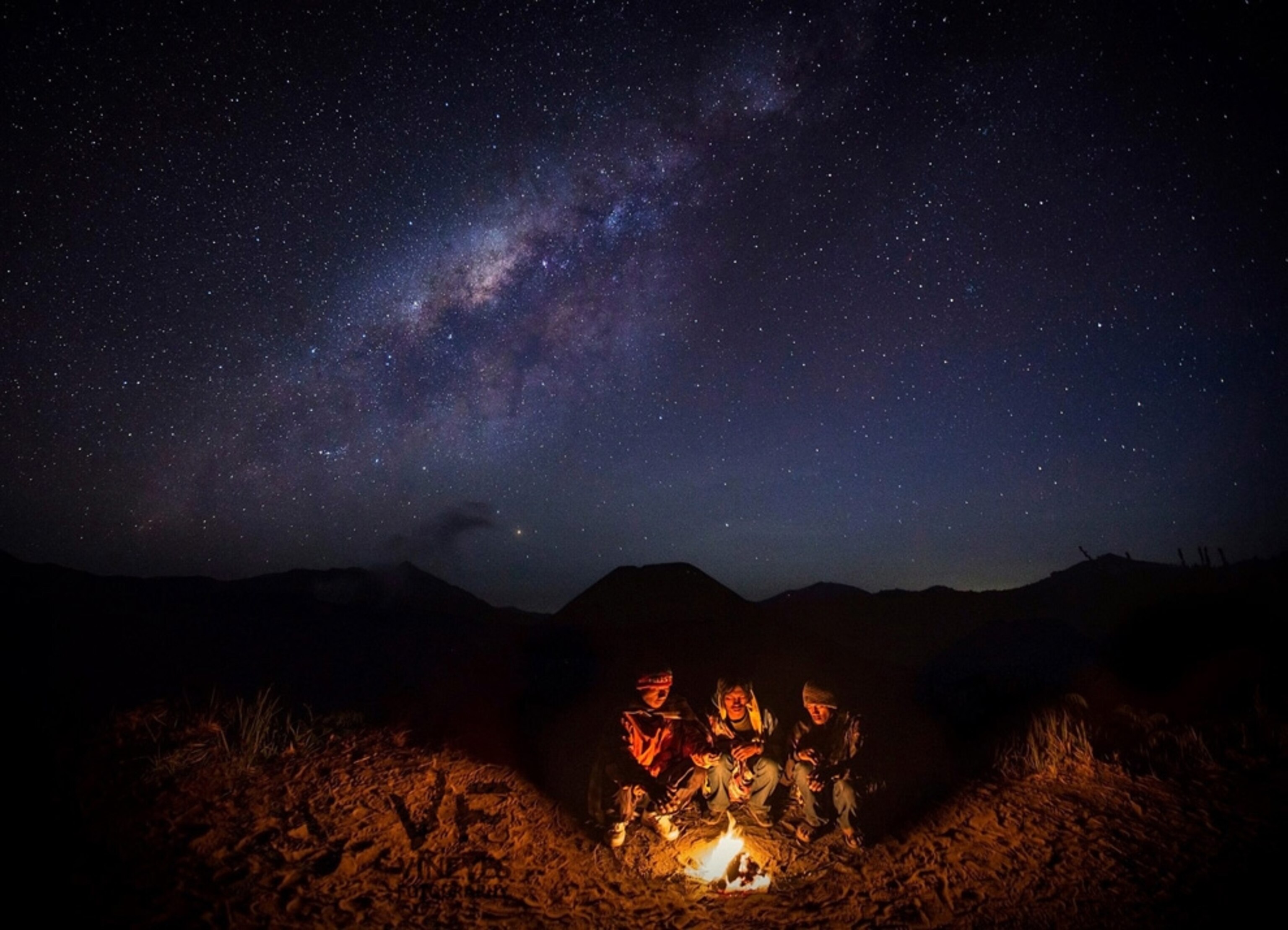 villagers huddled around campfire under the Milky Way in east Java