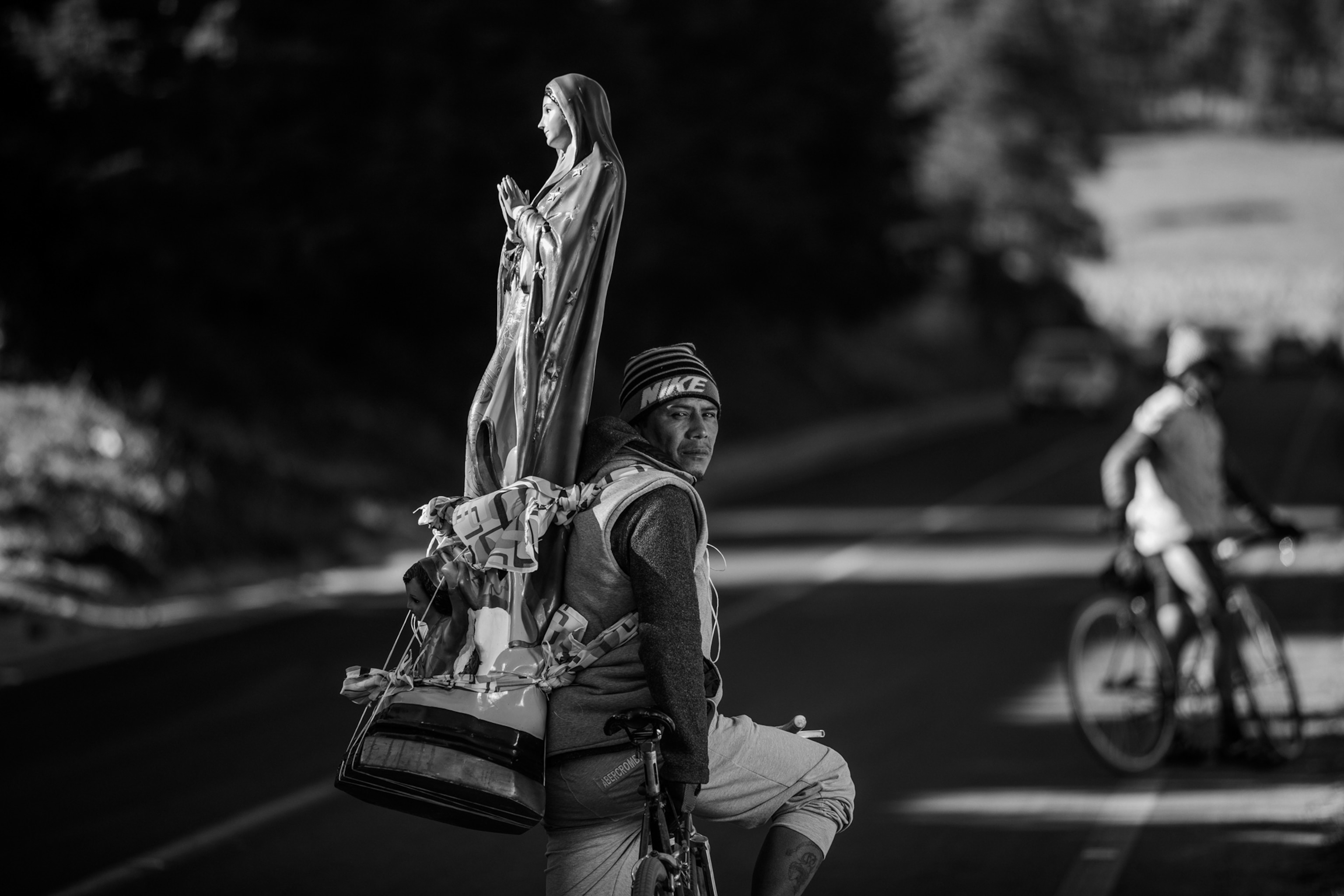A person on a bicycle with a statue on his back