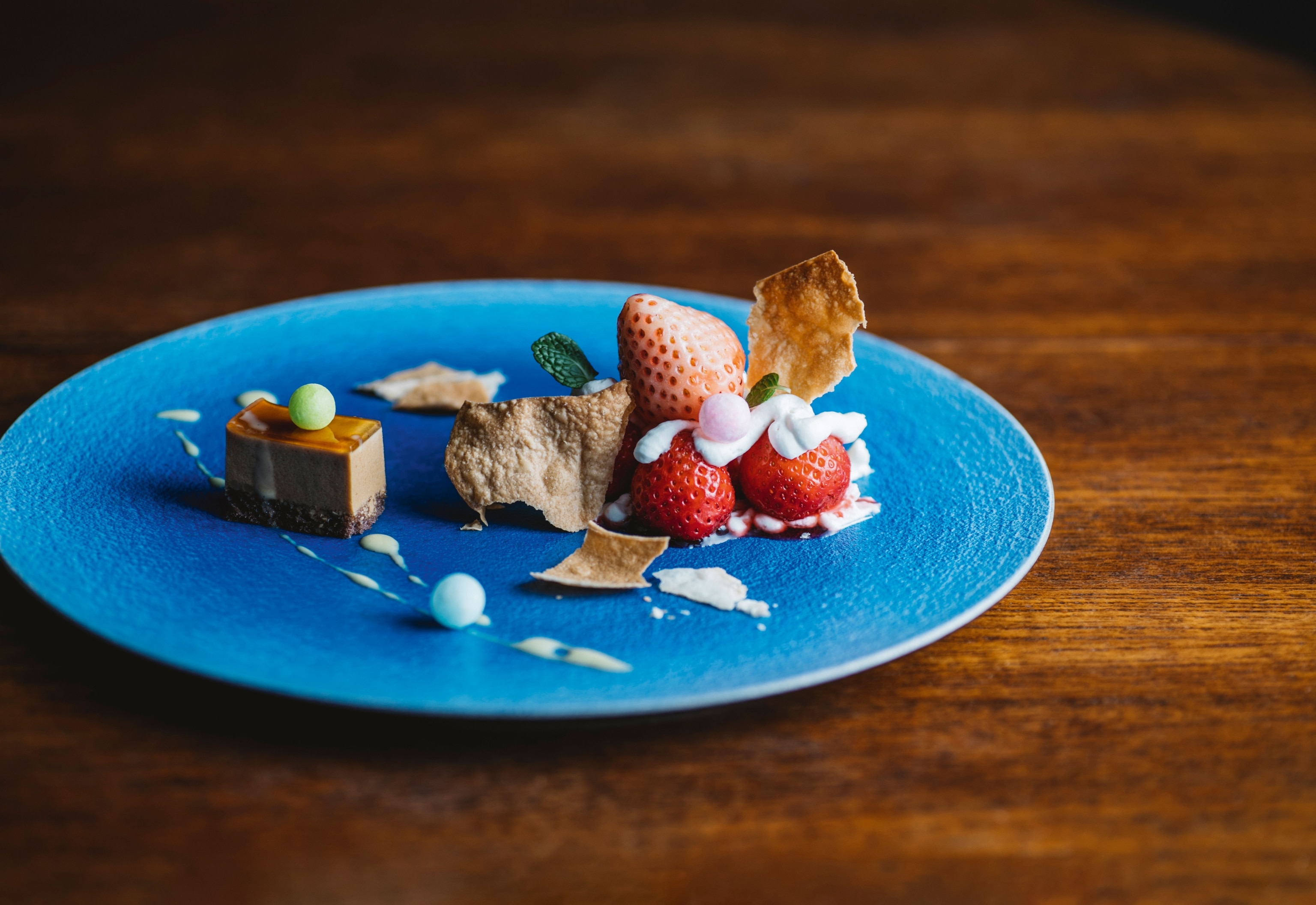 bright strawberry and caramel dessert on blue plate