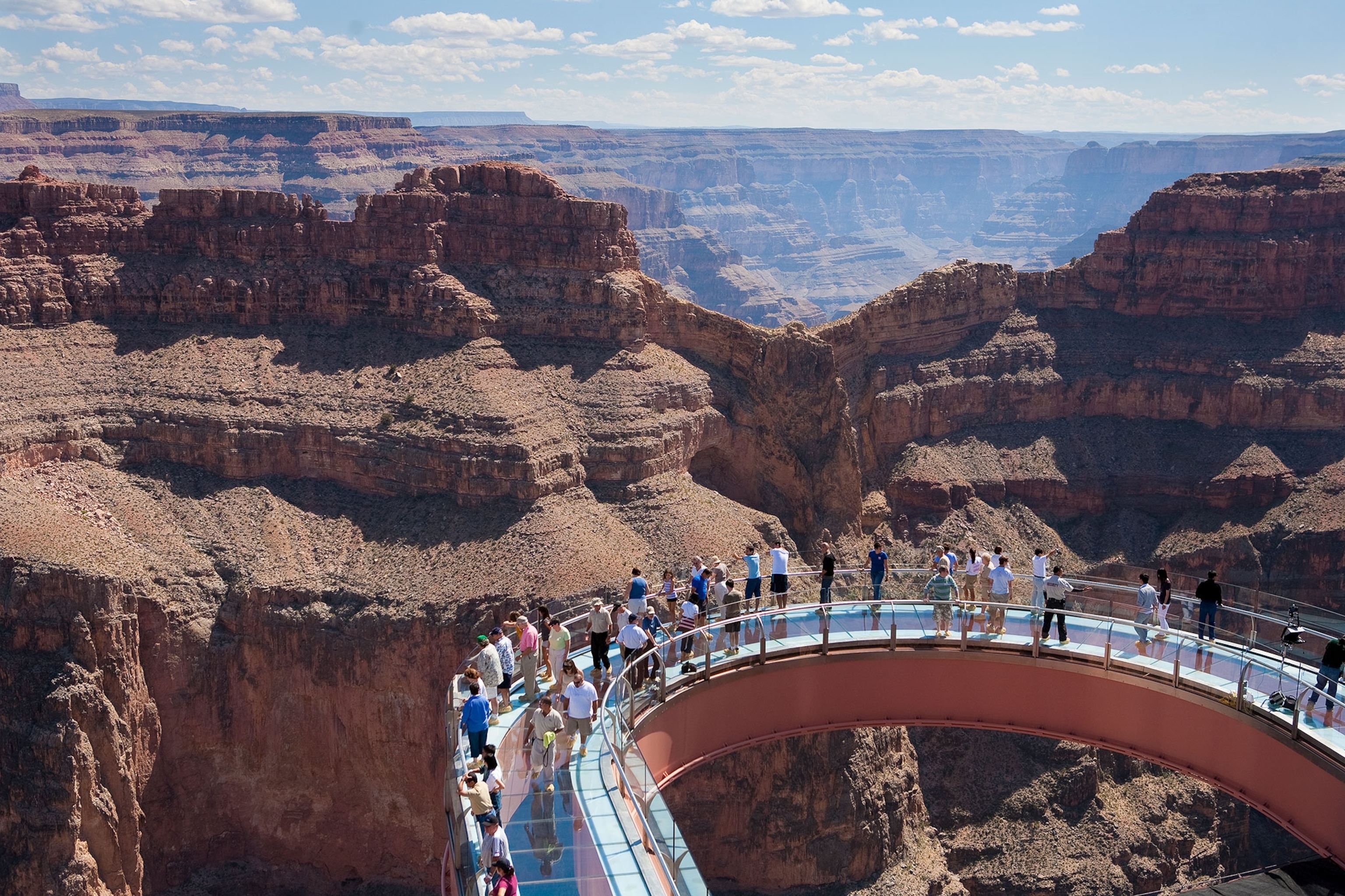 tourists standing on a skywalk over the Grand Canyon