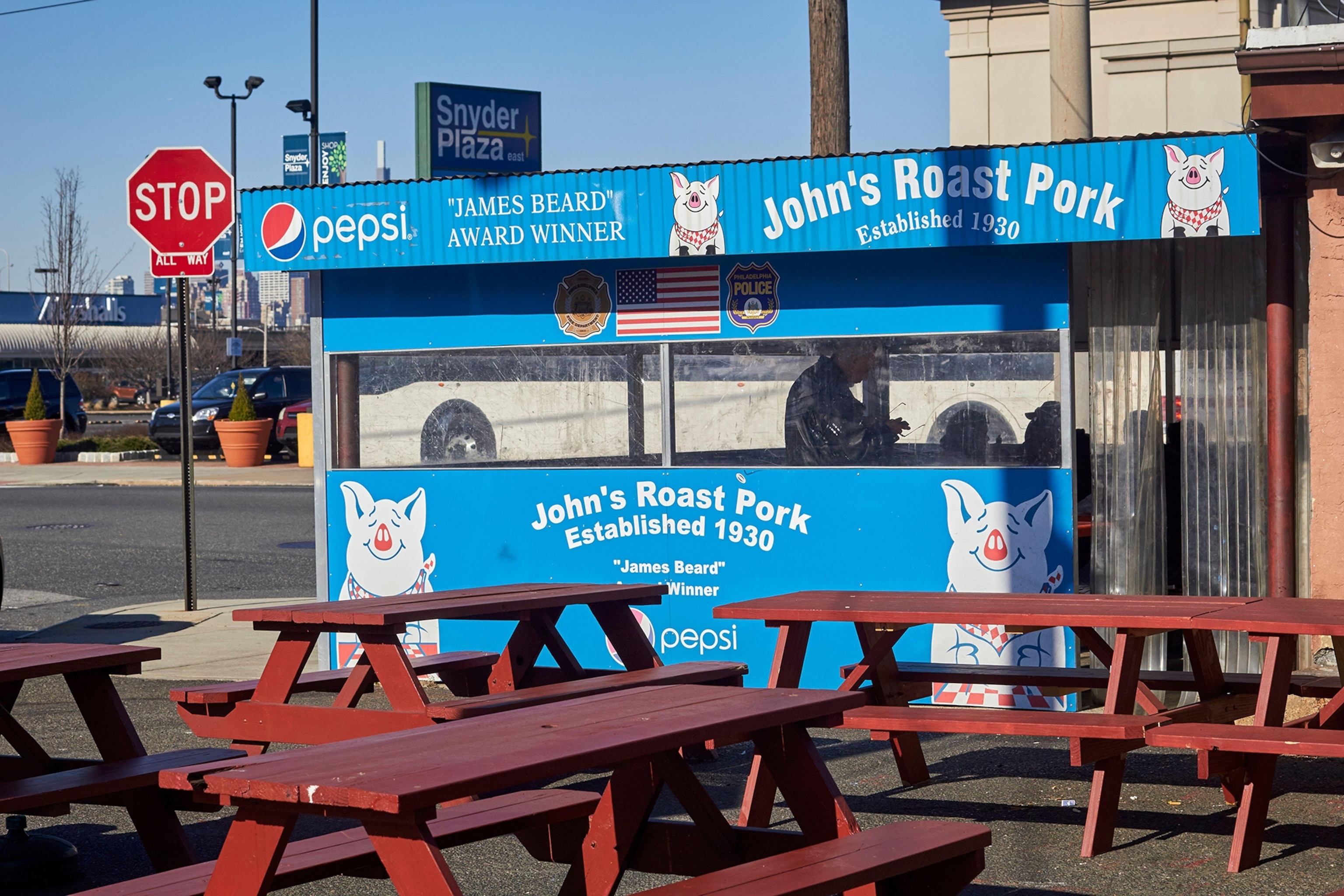 Exterior of a blue cafe with wooden picnic tables outside