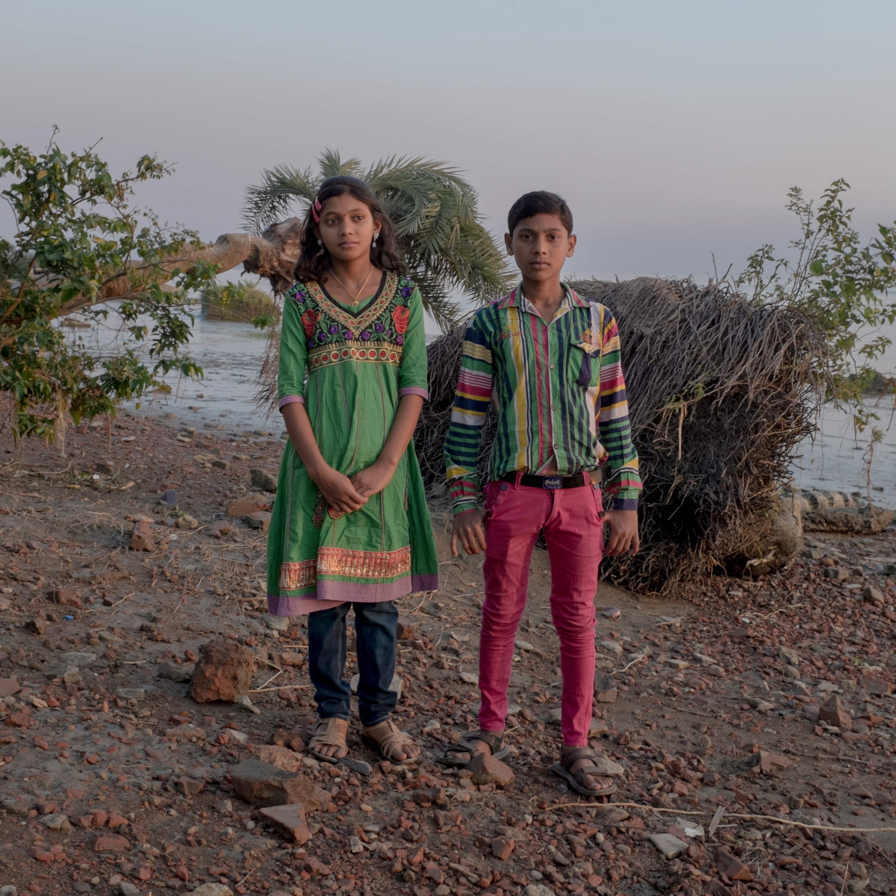 A brother and sister stroll along the Ganges river in West Bengal
