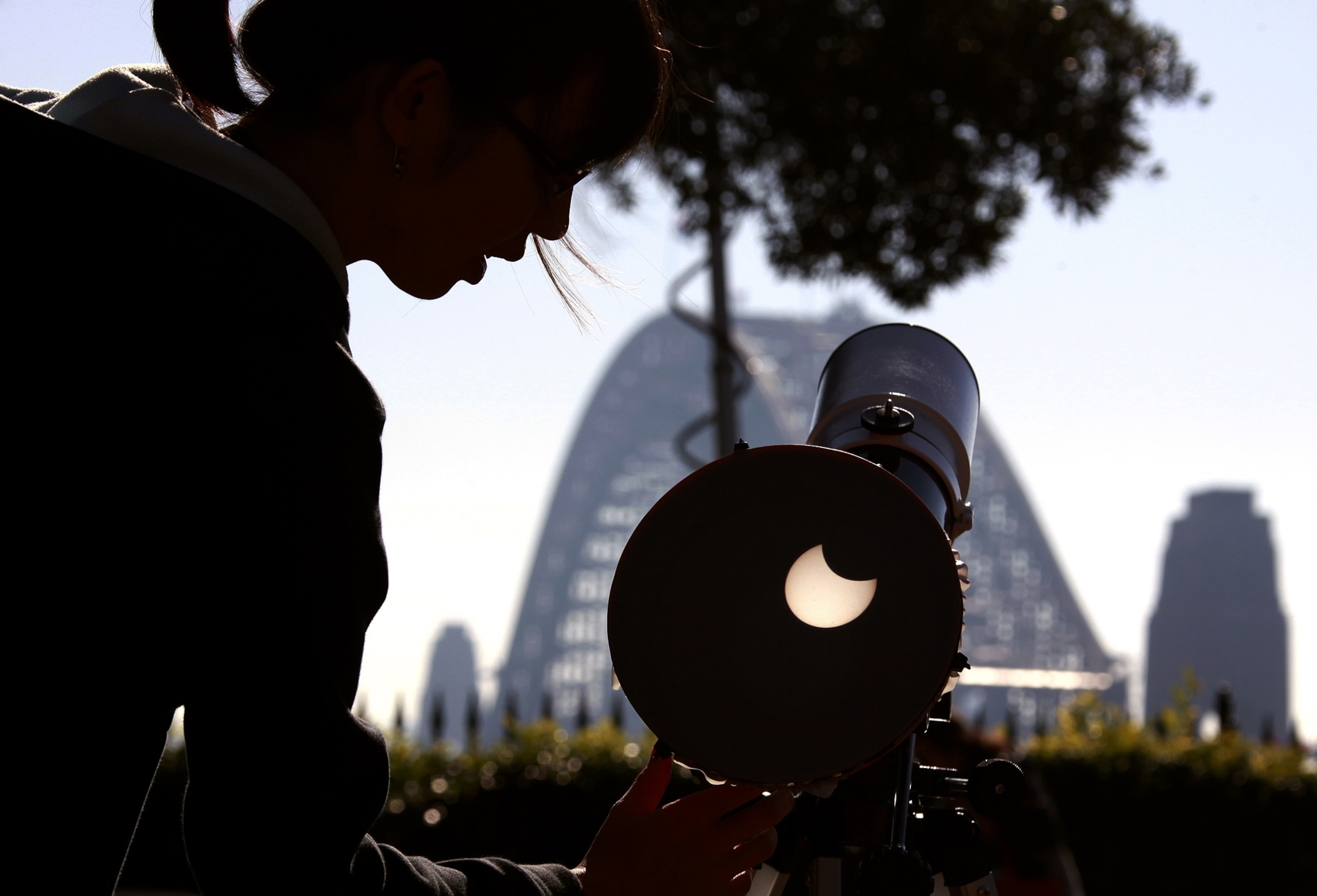 a woman with a telescope viewing the solar eclipse
