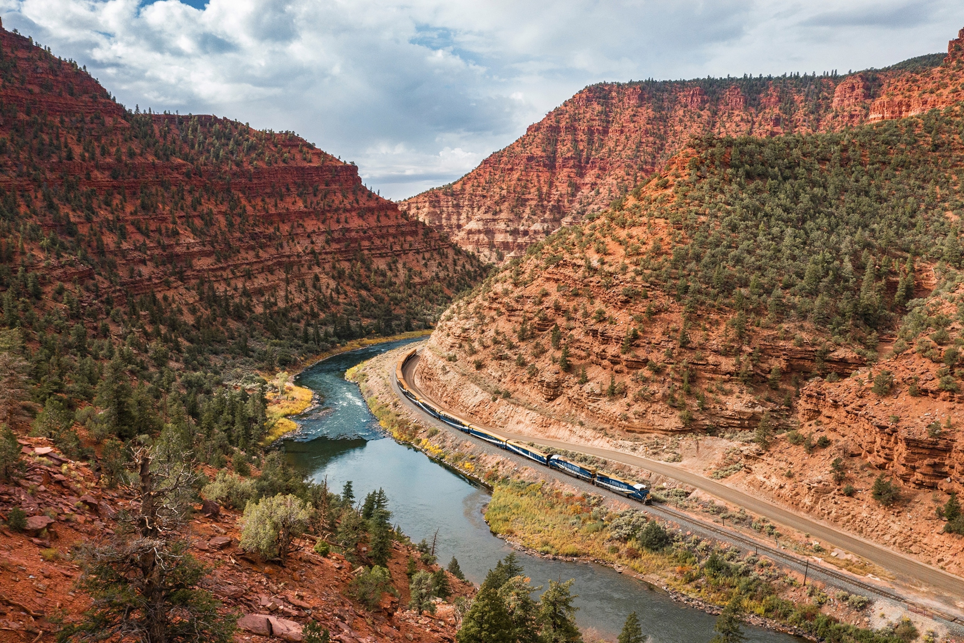 A canyon landscape with a railway running alongside a river in the valley.