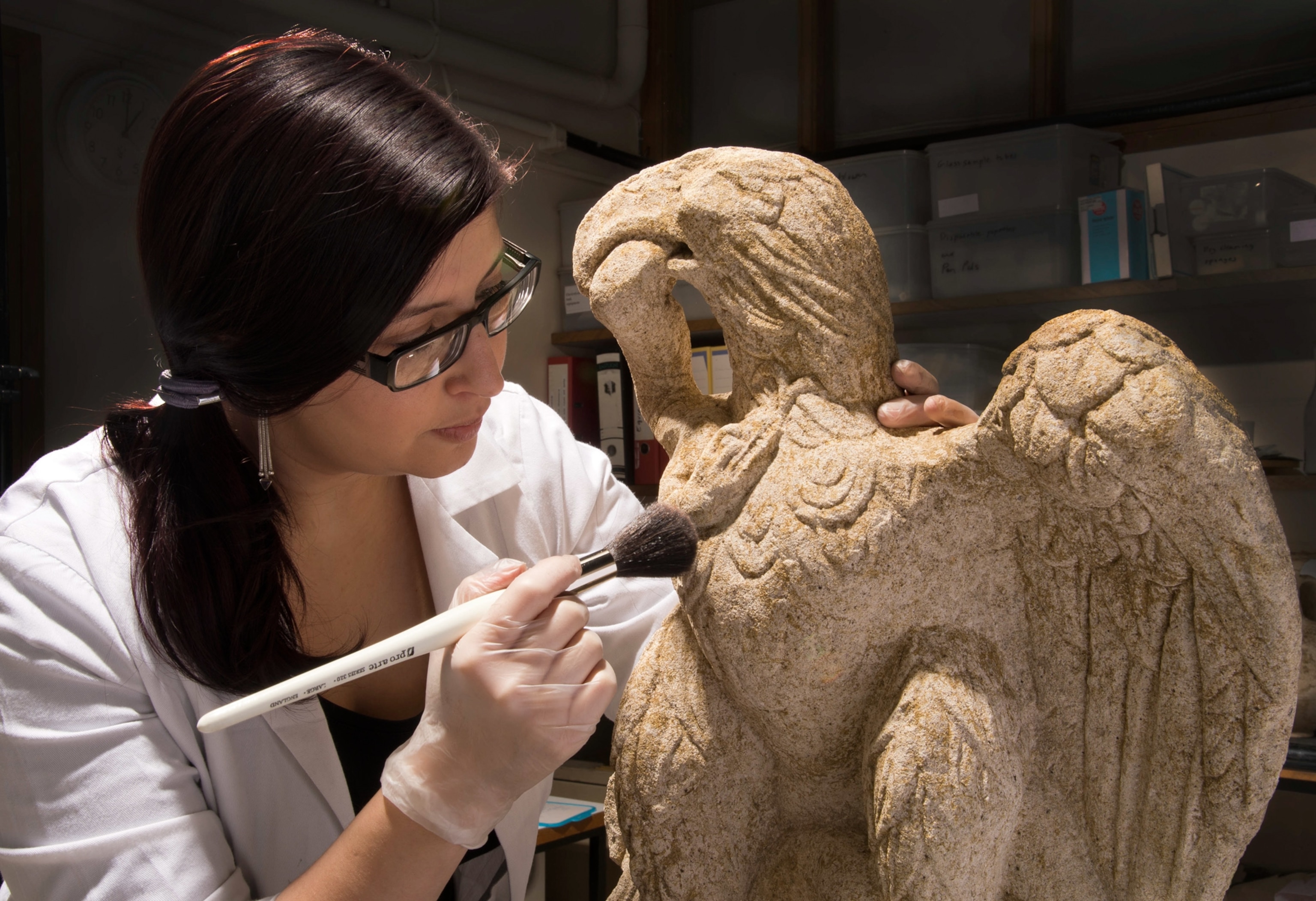 conservator Luisa Duarte dusting the Roman sculpture of an Eagle eating a serpent, dating approximately from I or II AD in London.