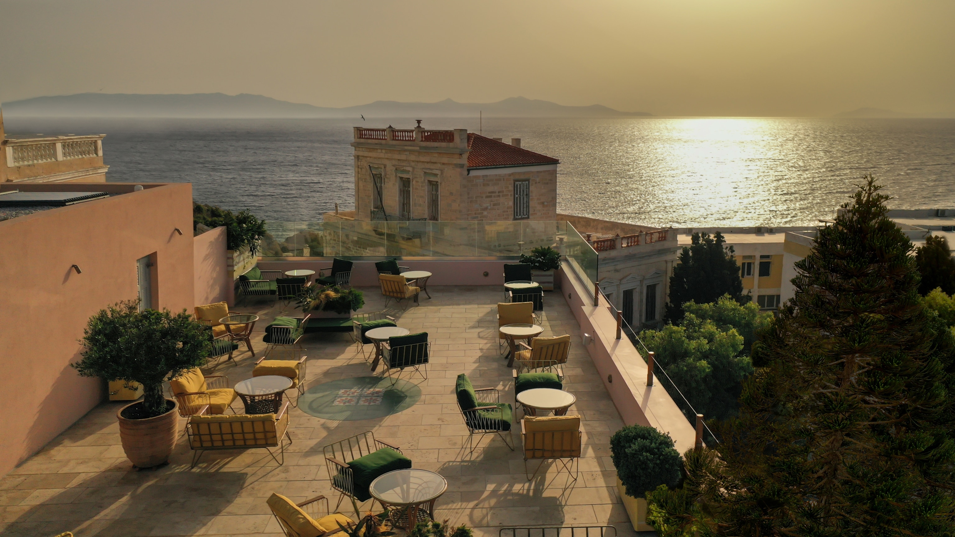 Tables and chairs on a building rooftop restaurant overlooking the sea