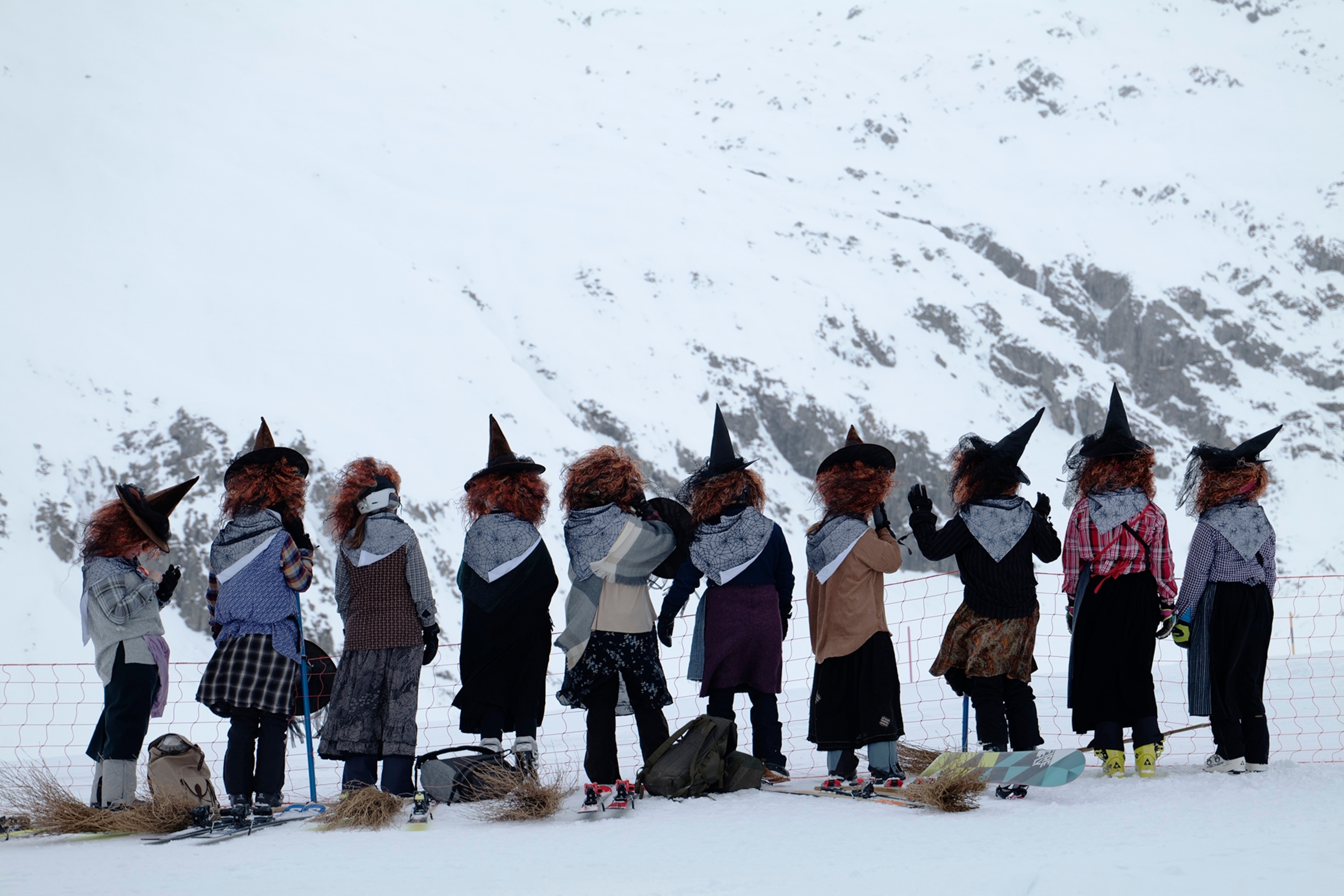 A team of ten skiers dressed as witches cheer from the sidelines of a ski race during the Belalp Hexen festival in Belalp, Switzerland. The festival includes races and witch themed activities.