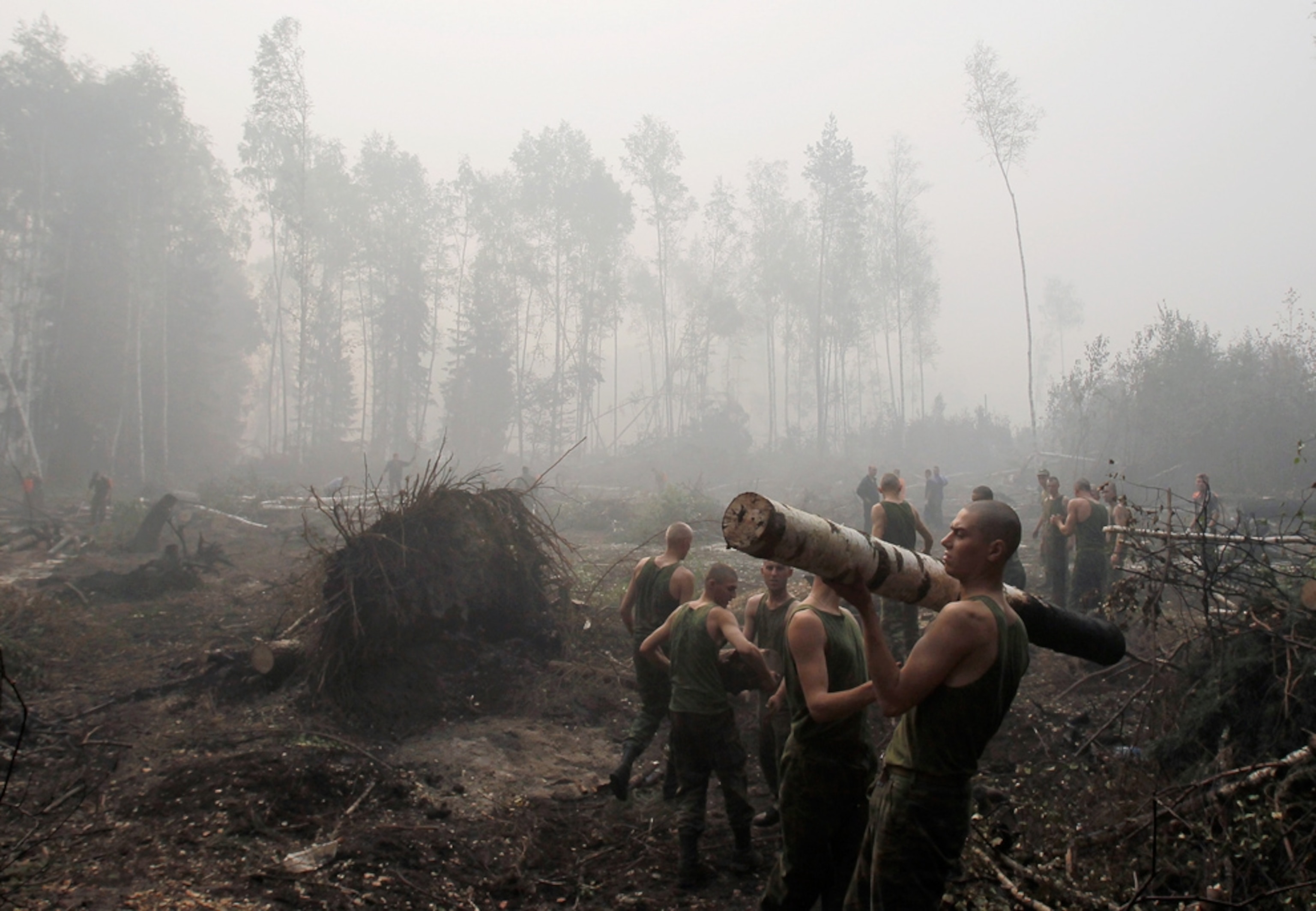Picture of servicemen cleaning up after a wildfire in Russia, where a record heat wave has sparked hundreds of wildfires.