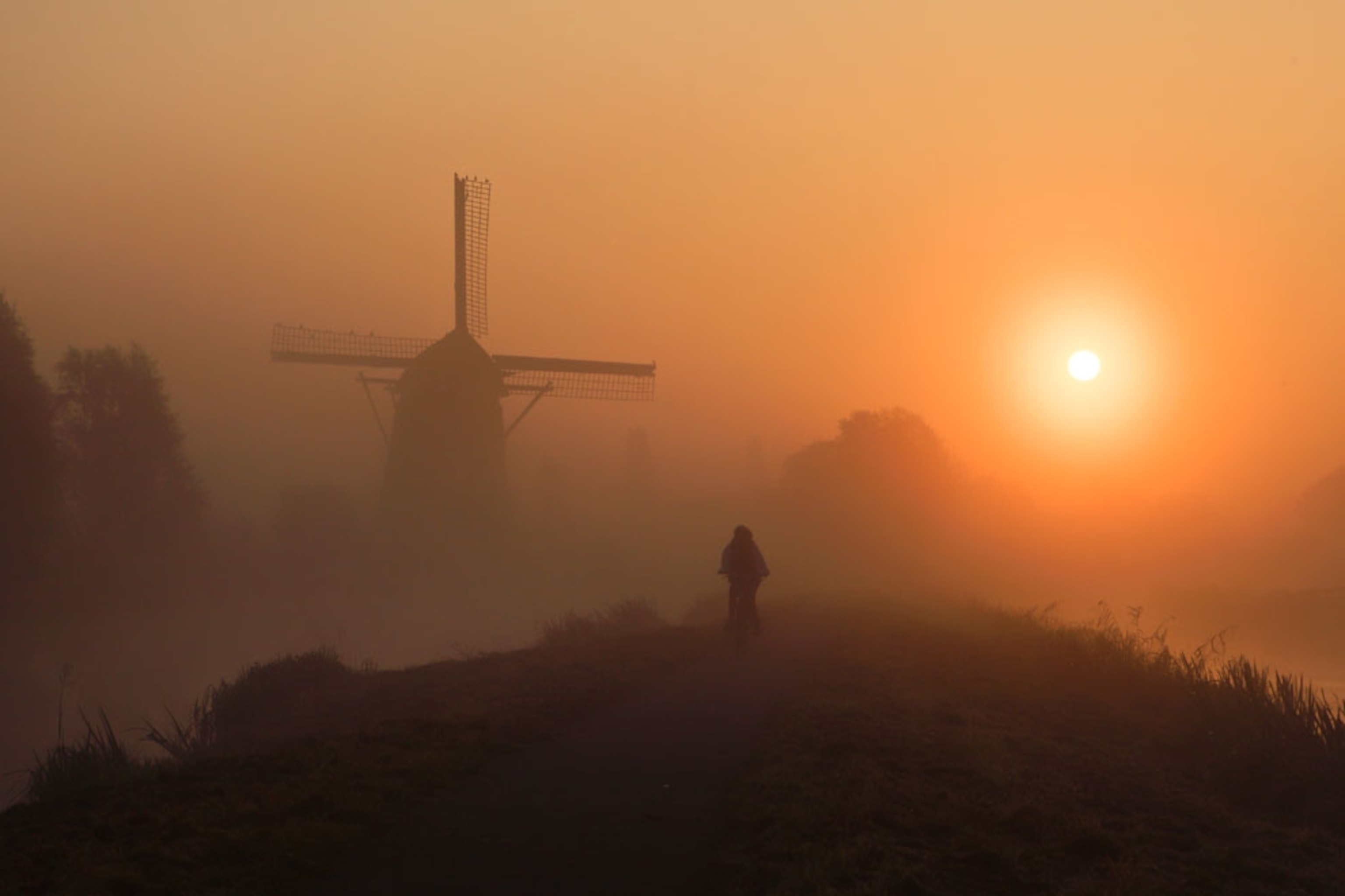 Windmills seen through misty morning at sunrise in Netherlands