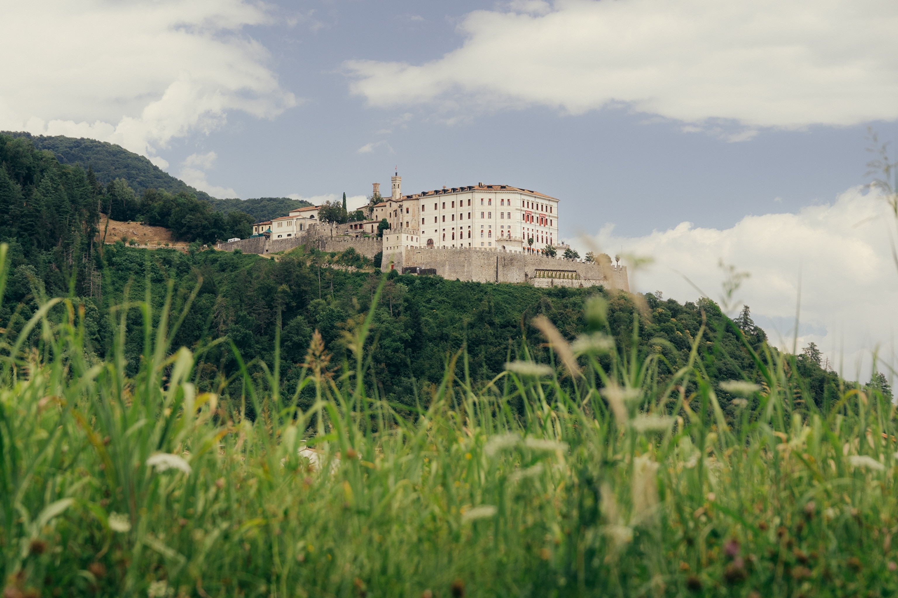 An old stone castle on the top of a lush hill.