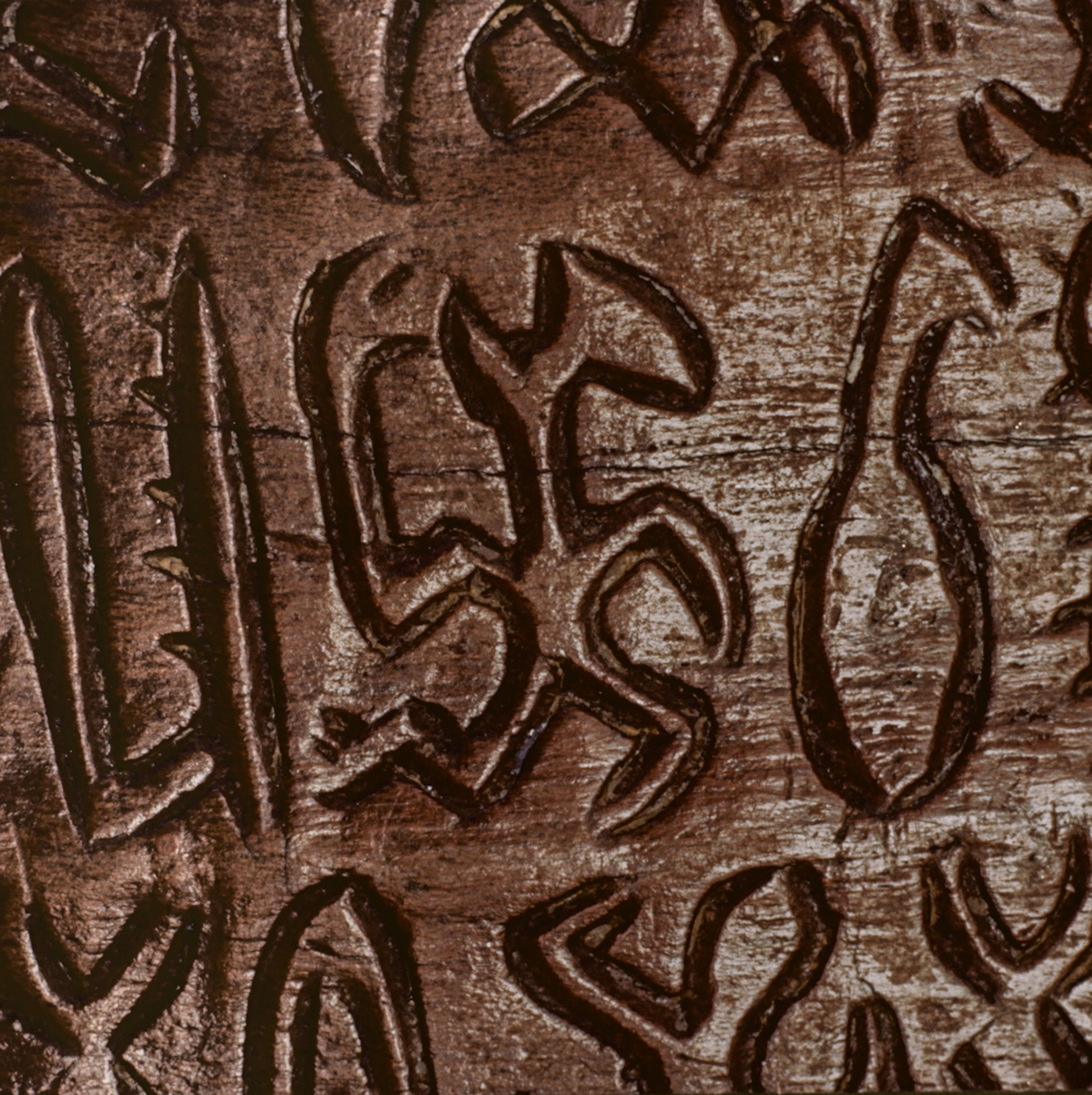 A close up of a wooden object with writing carved into it.