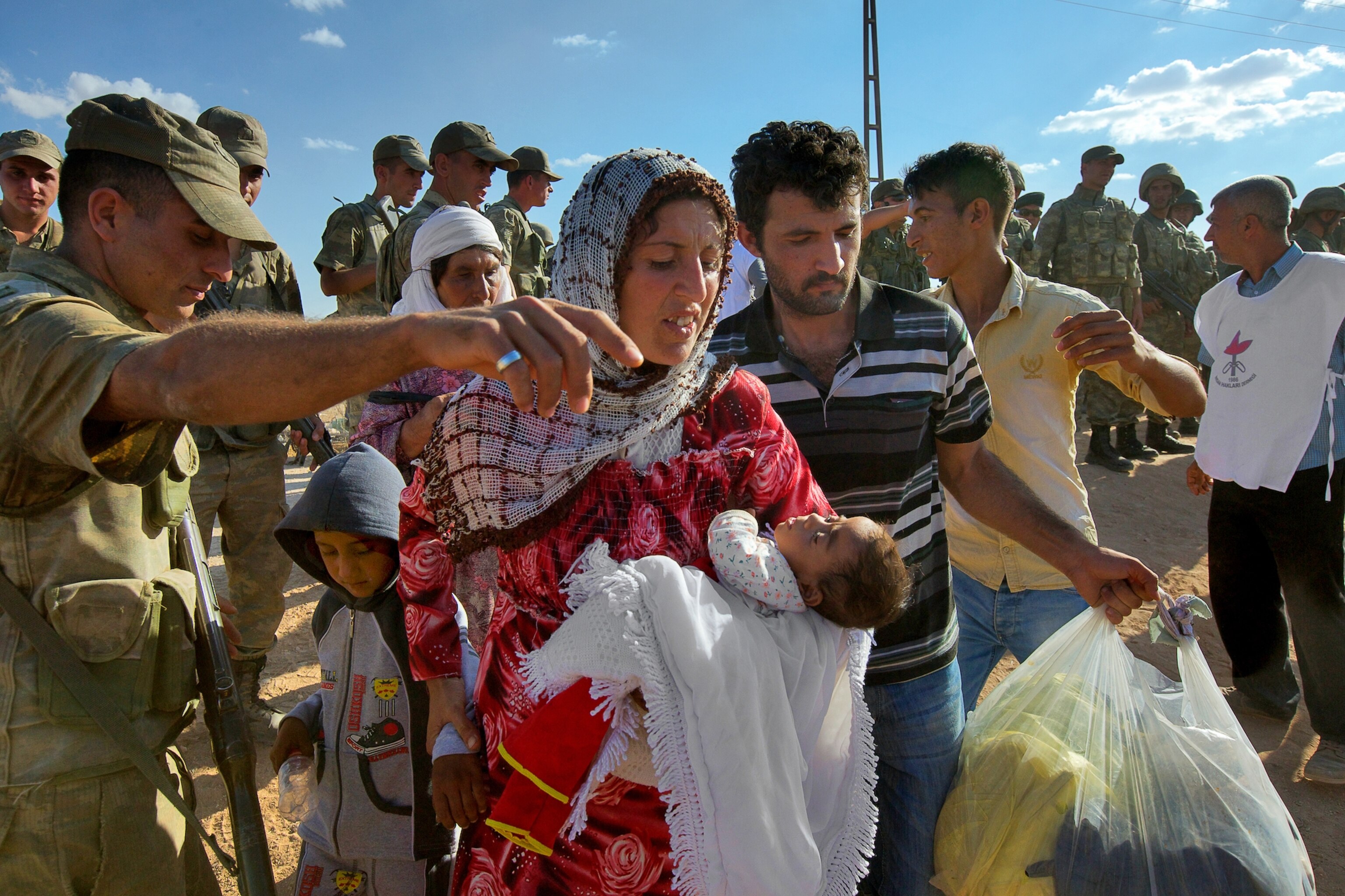 a Syrian women carrying a baby after fleeing to Turkey with thousands of others.