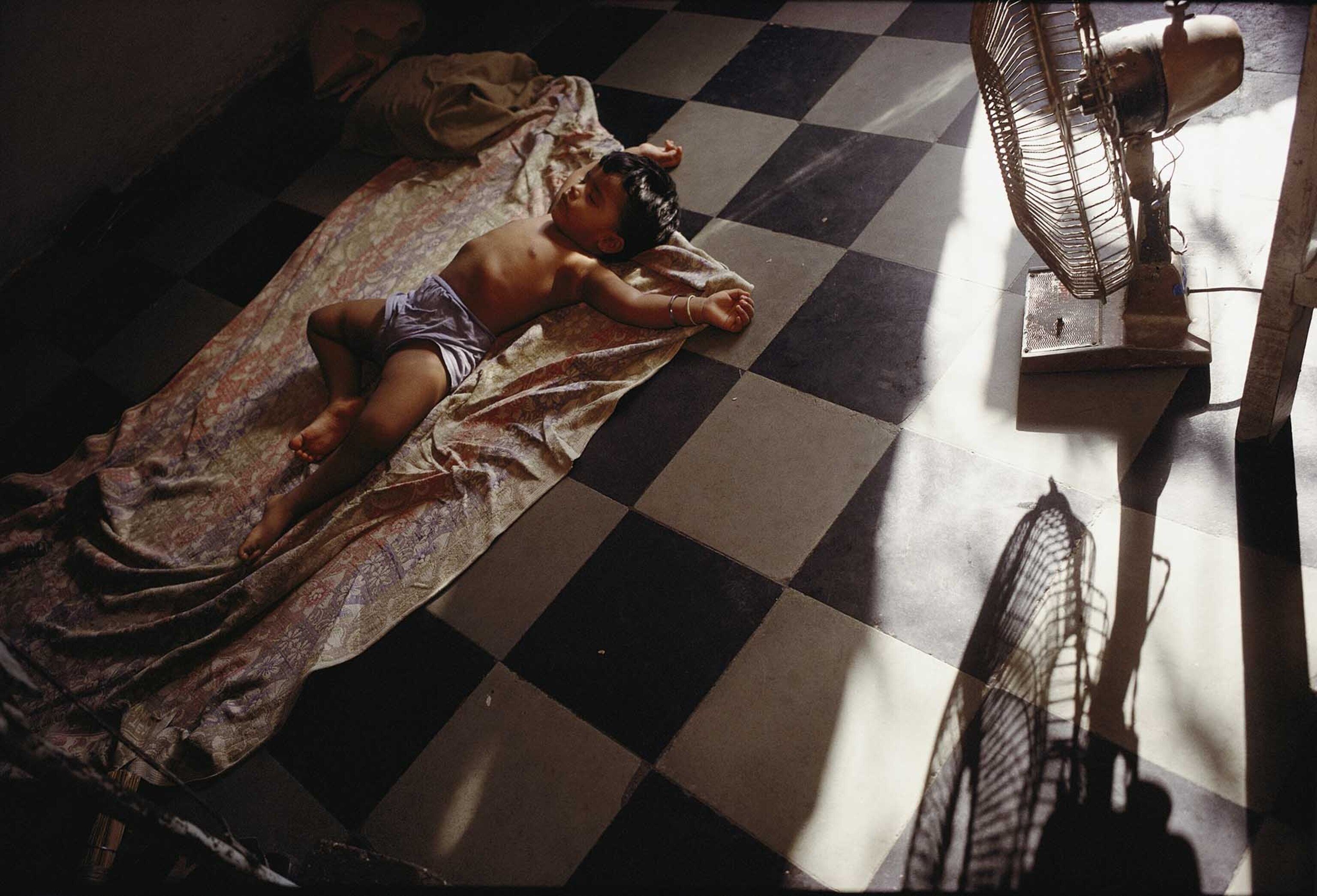 a fan offers a bit of relief to a sleeping Untouchable child