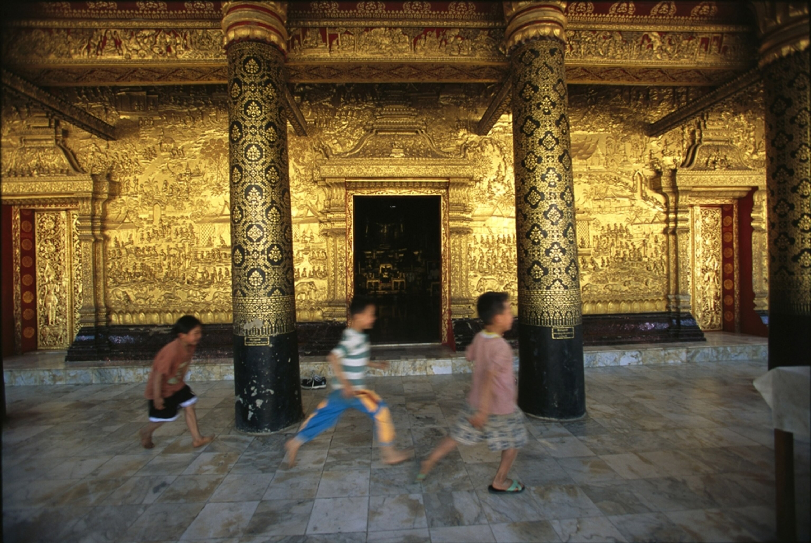 three boys running at Wat Mai, Luang Prabang, Laos