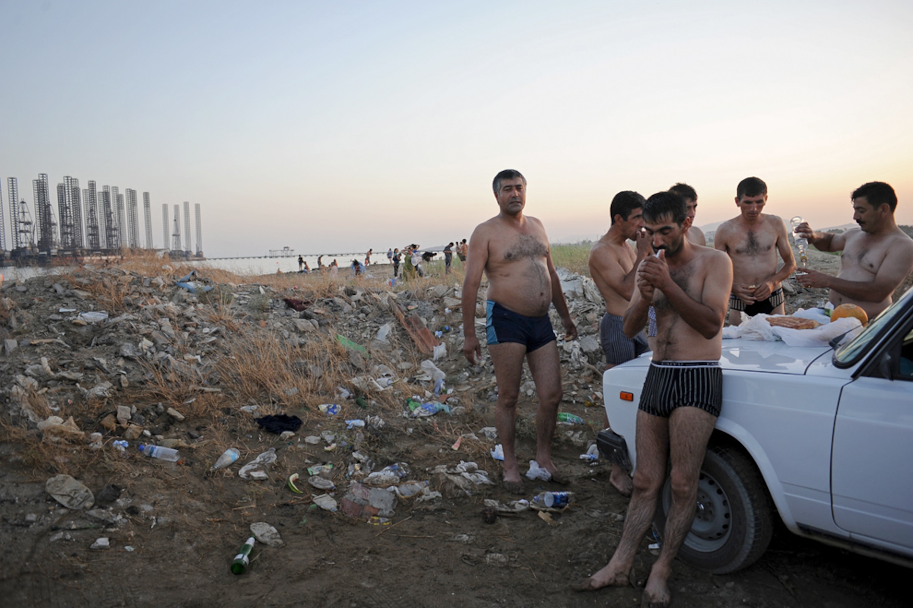 Men picnic with vodka on the hood of a car on the Caspian beach in Sixov, Azerbaijan