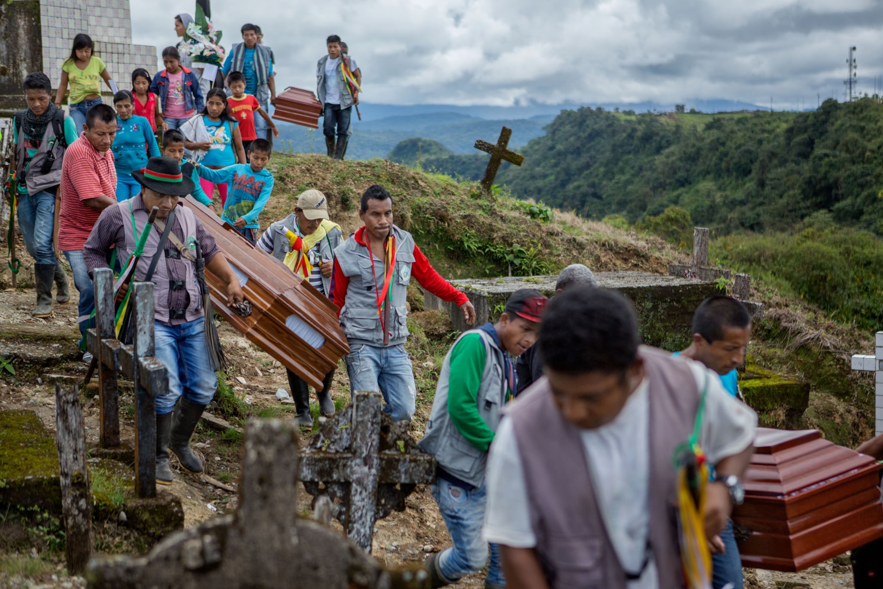 a group of men and women carrying coffins on the side of a hill.