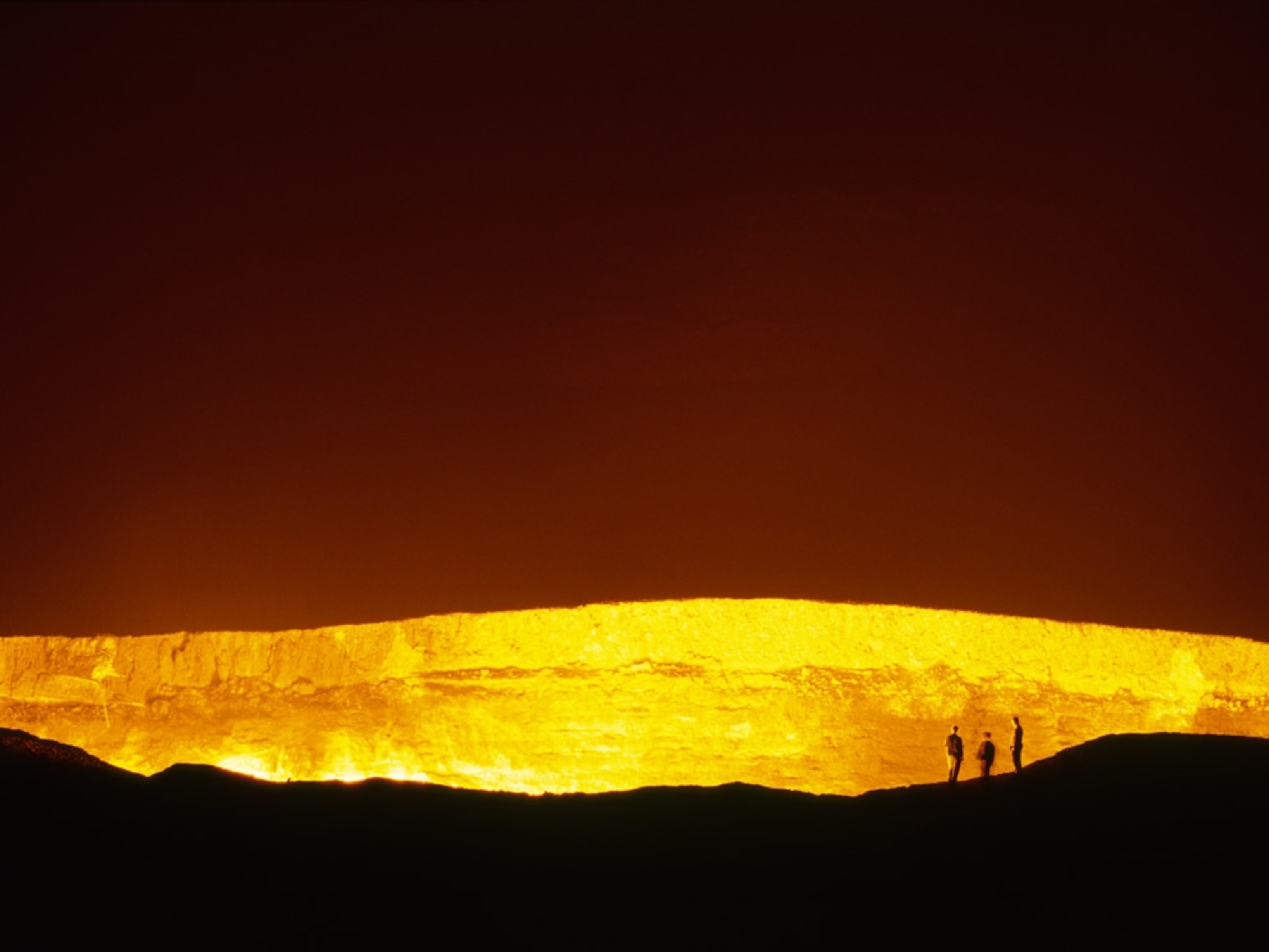 People standing near a burning crater