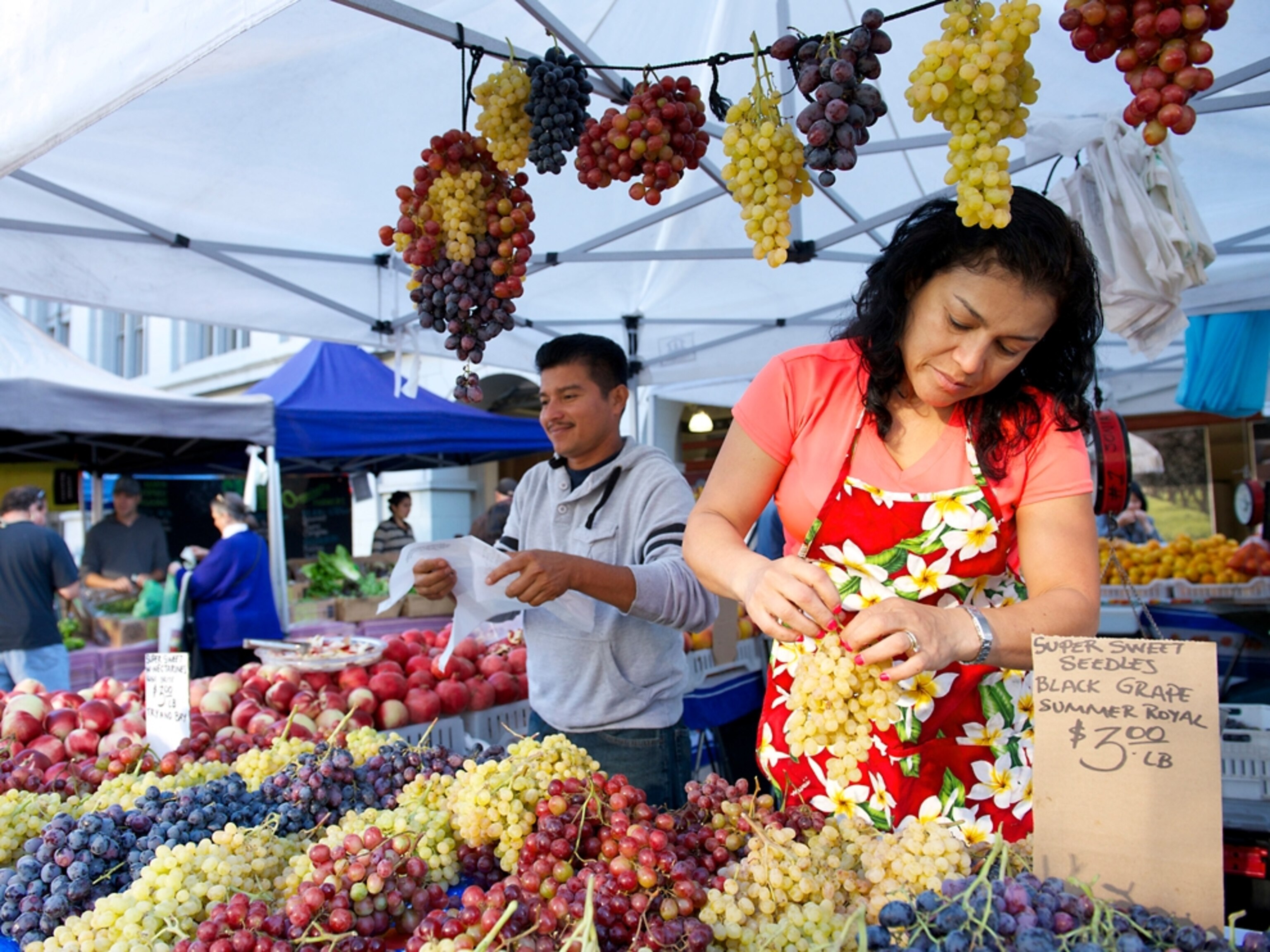 a vendor selling grapes at a farmers market