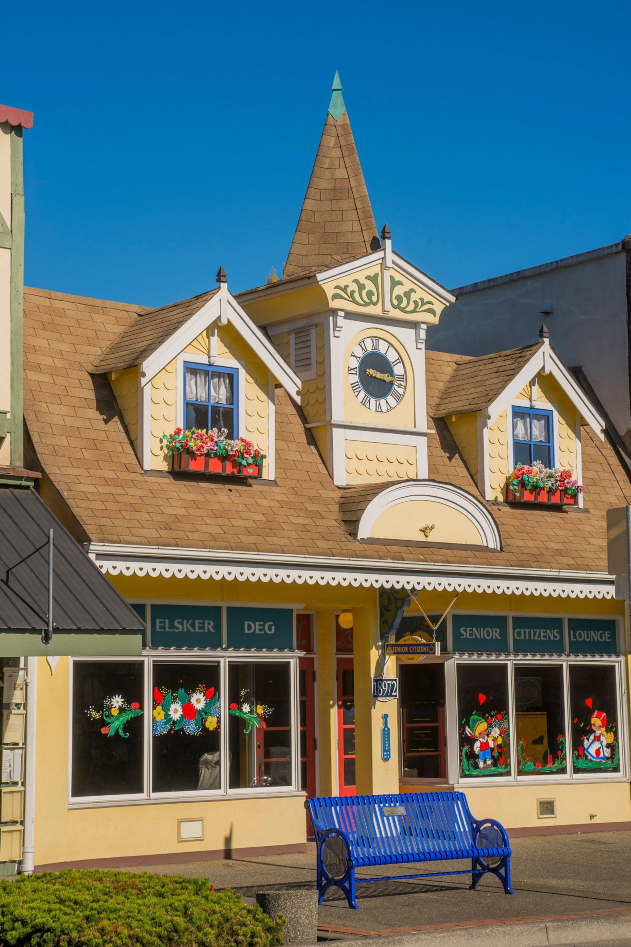 Fairy tale-like building with a clock tower and peaked roof, decorated with flower boxes