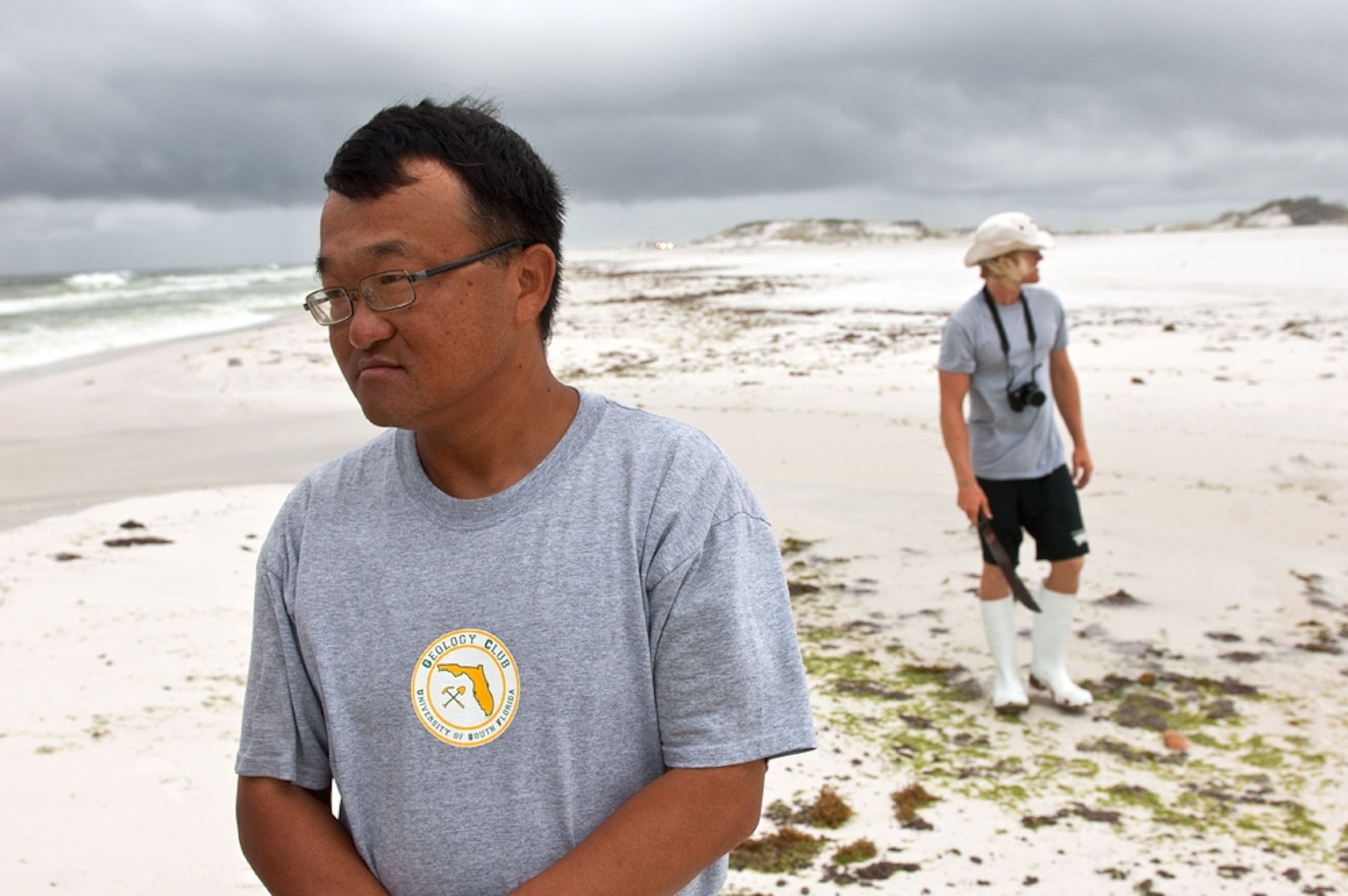 University of South Florida coastal geologist Ping Wang, who led the Pensacola Beach digs, stands amid beach-top tarballs and tar mats with team member Stoddard Pickrel (background) on July 1.