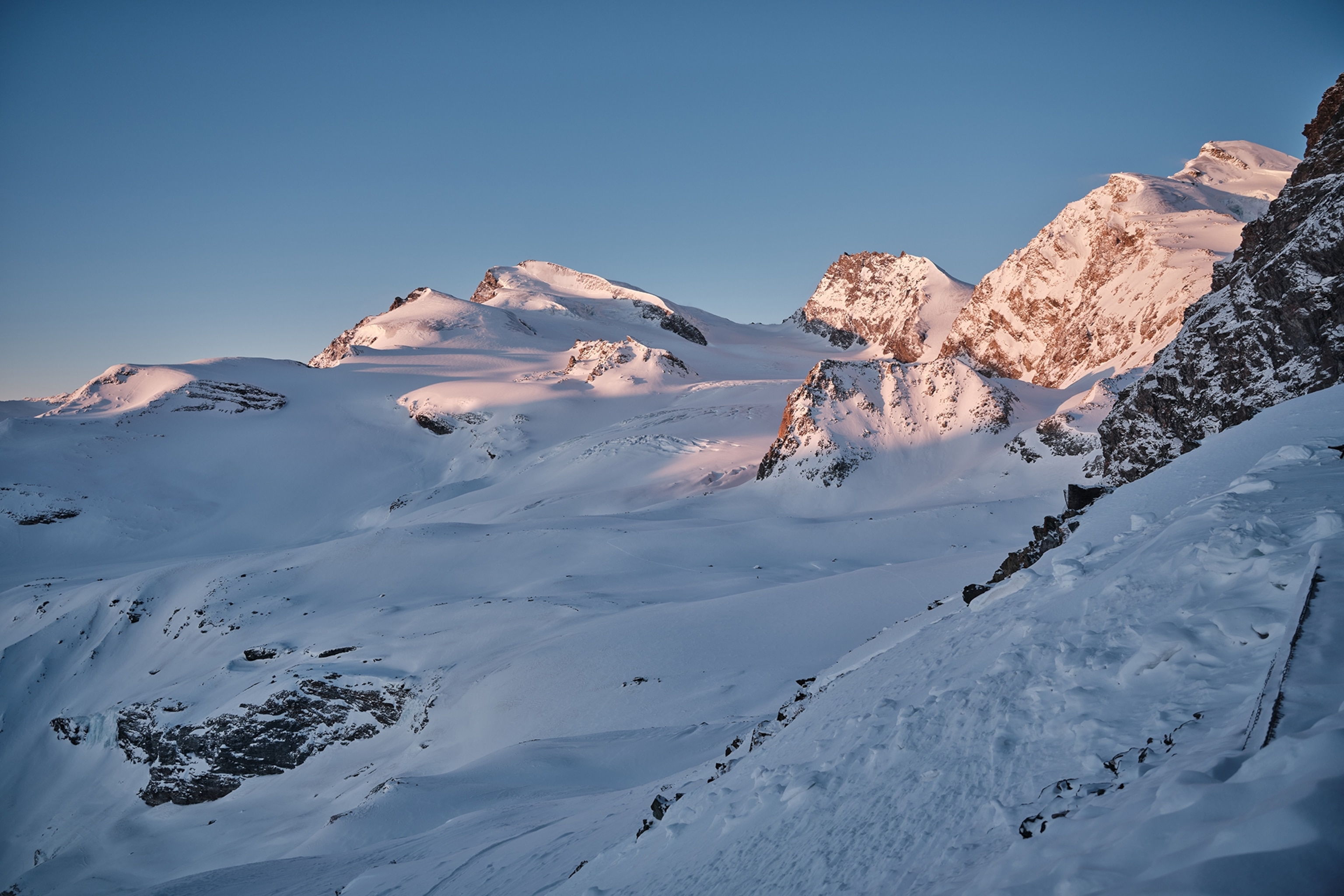 The sun rises over the snowy peak of the Allalin glacier.