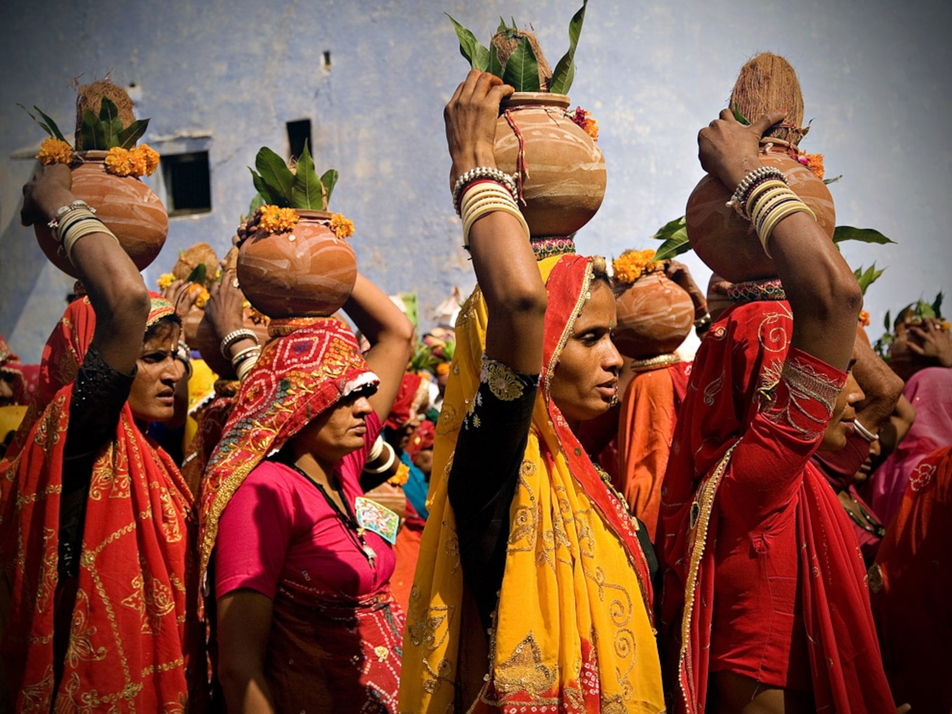 Women in colorful saris carrying flowerpots
