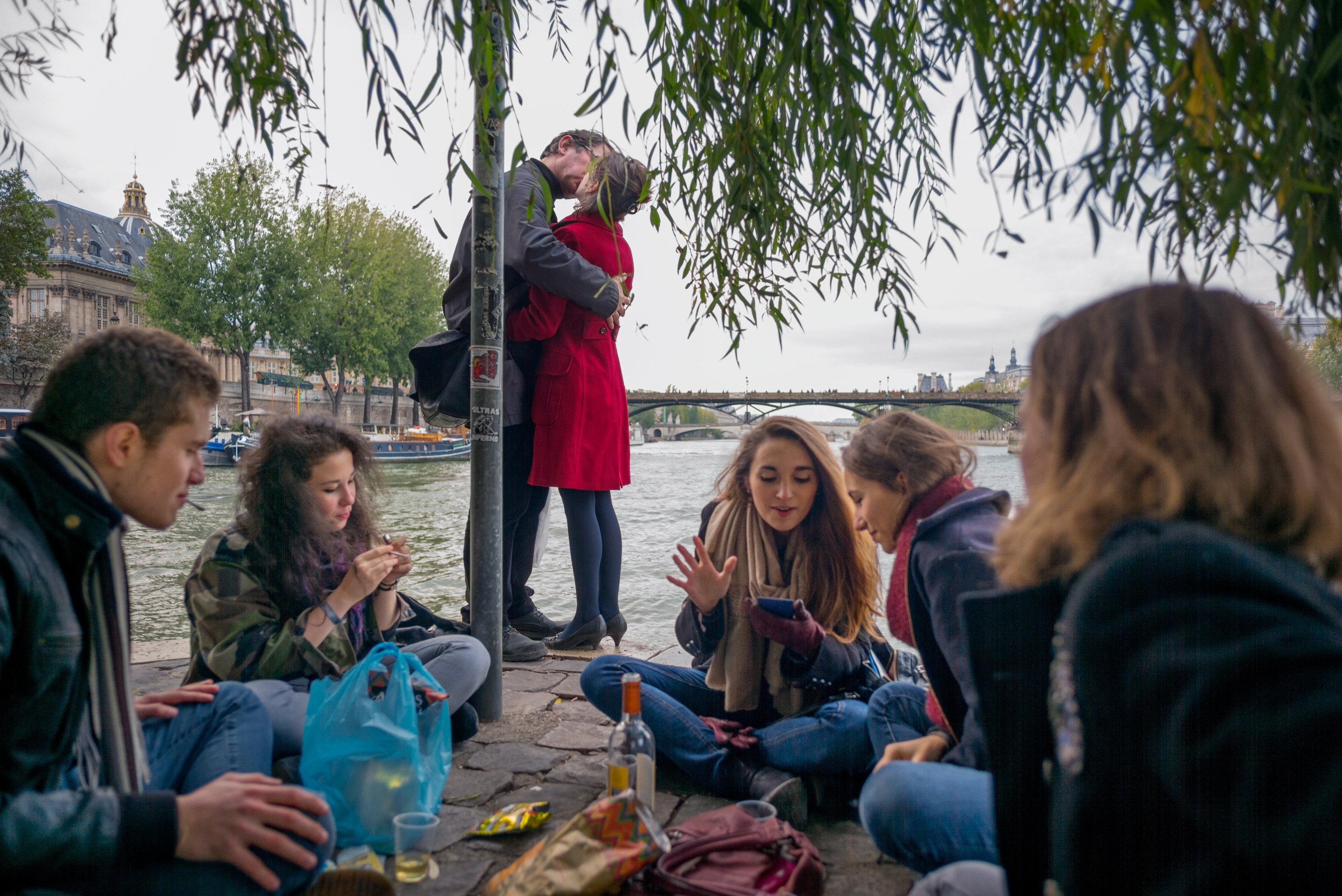 A couple kiss on the bank of the Seine River.