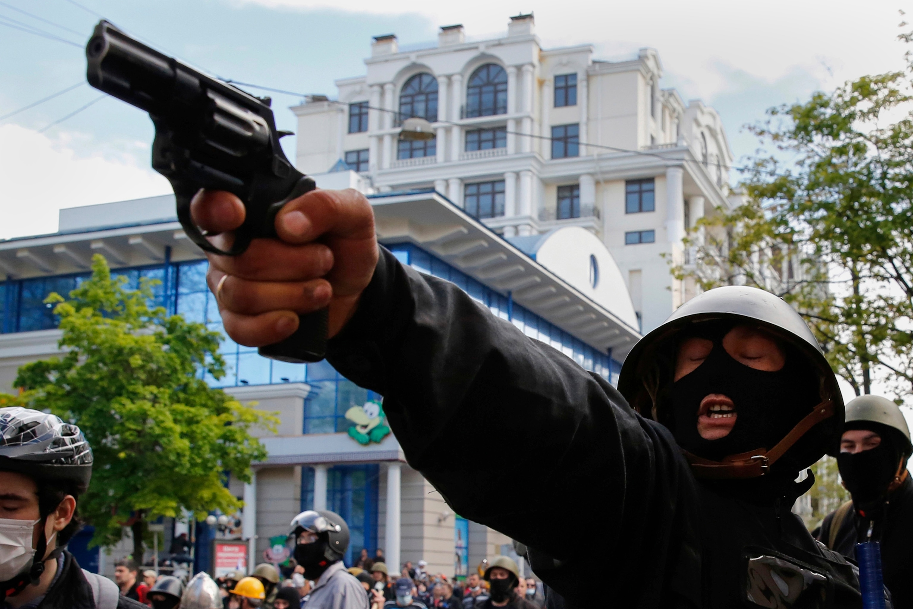 a pro-Russian activist aiming a pistol at supporters of the Kiev government.