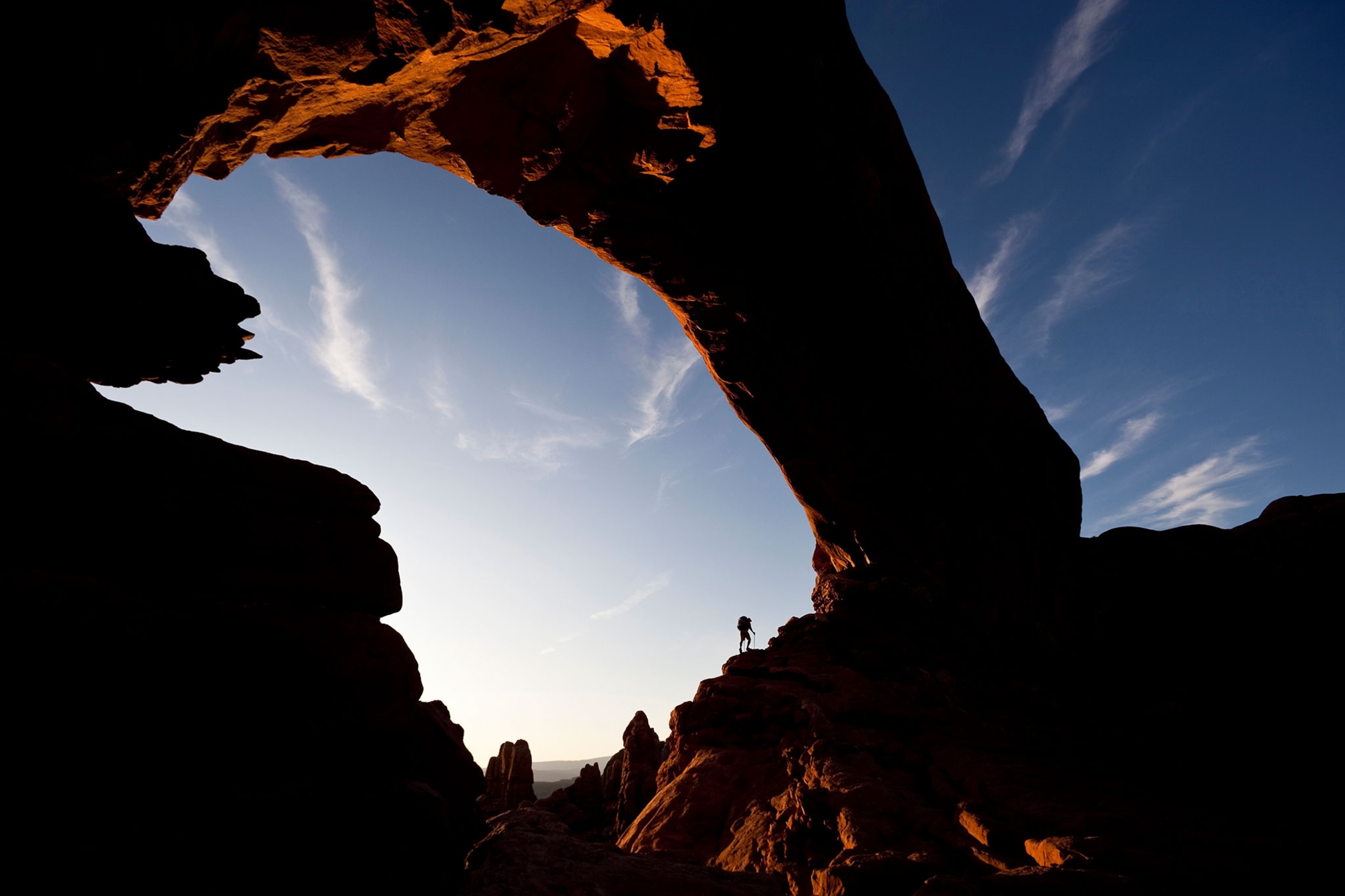a hiker beneath North Window Arch in Arches National Park, Utah