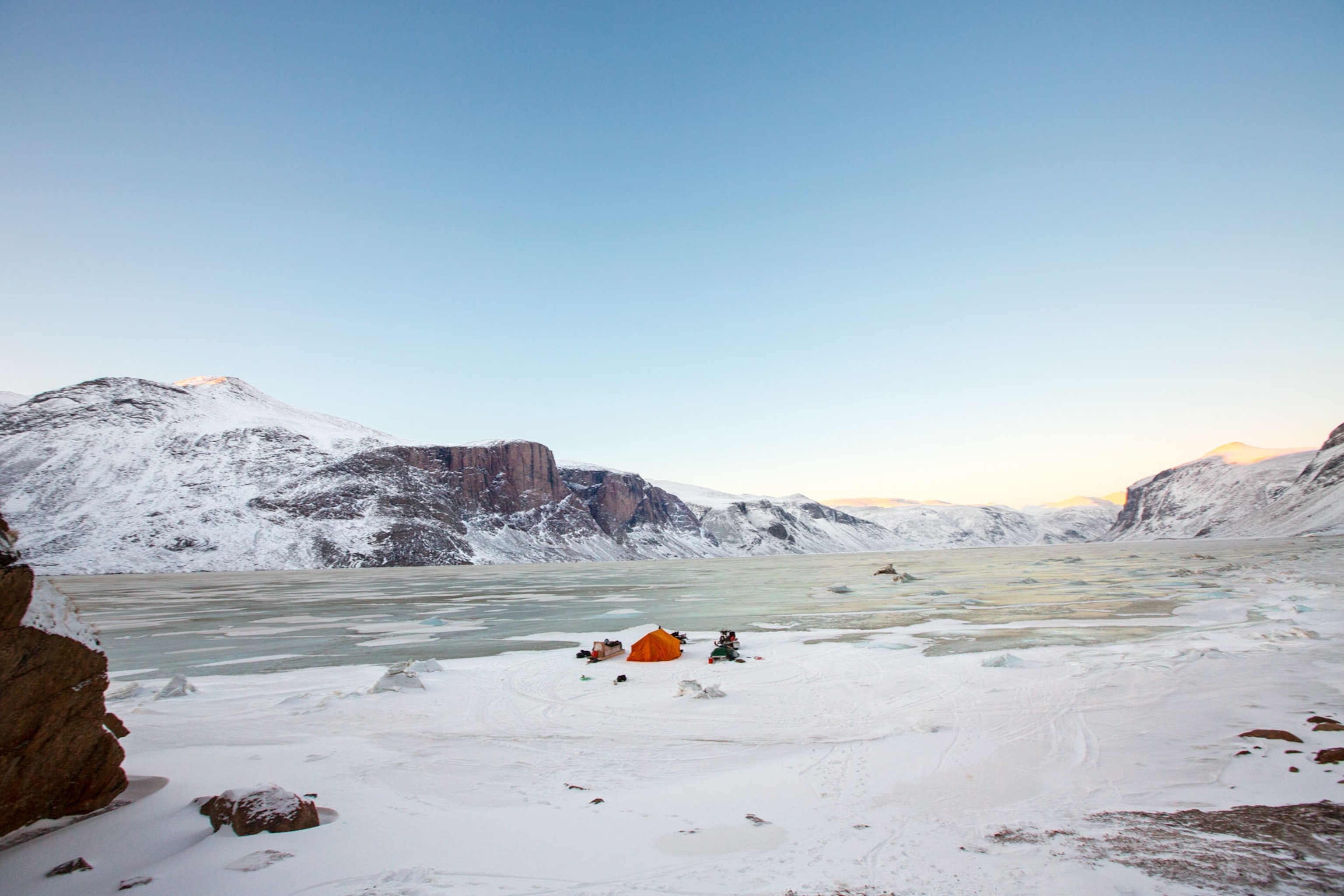 an orange tent setup on frozen ice in the arctic