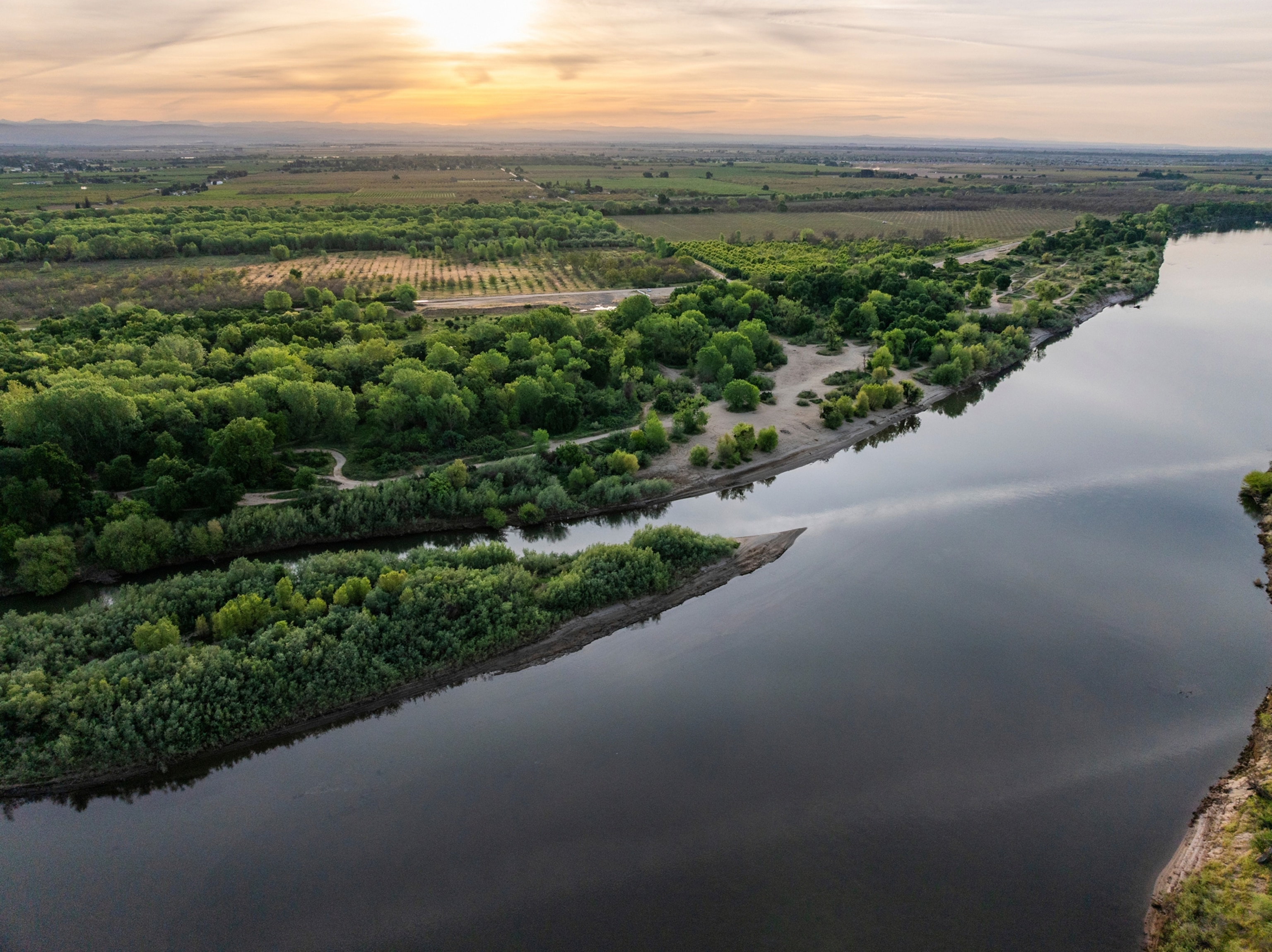 A river is seen amongst large stretches of green land.