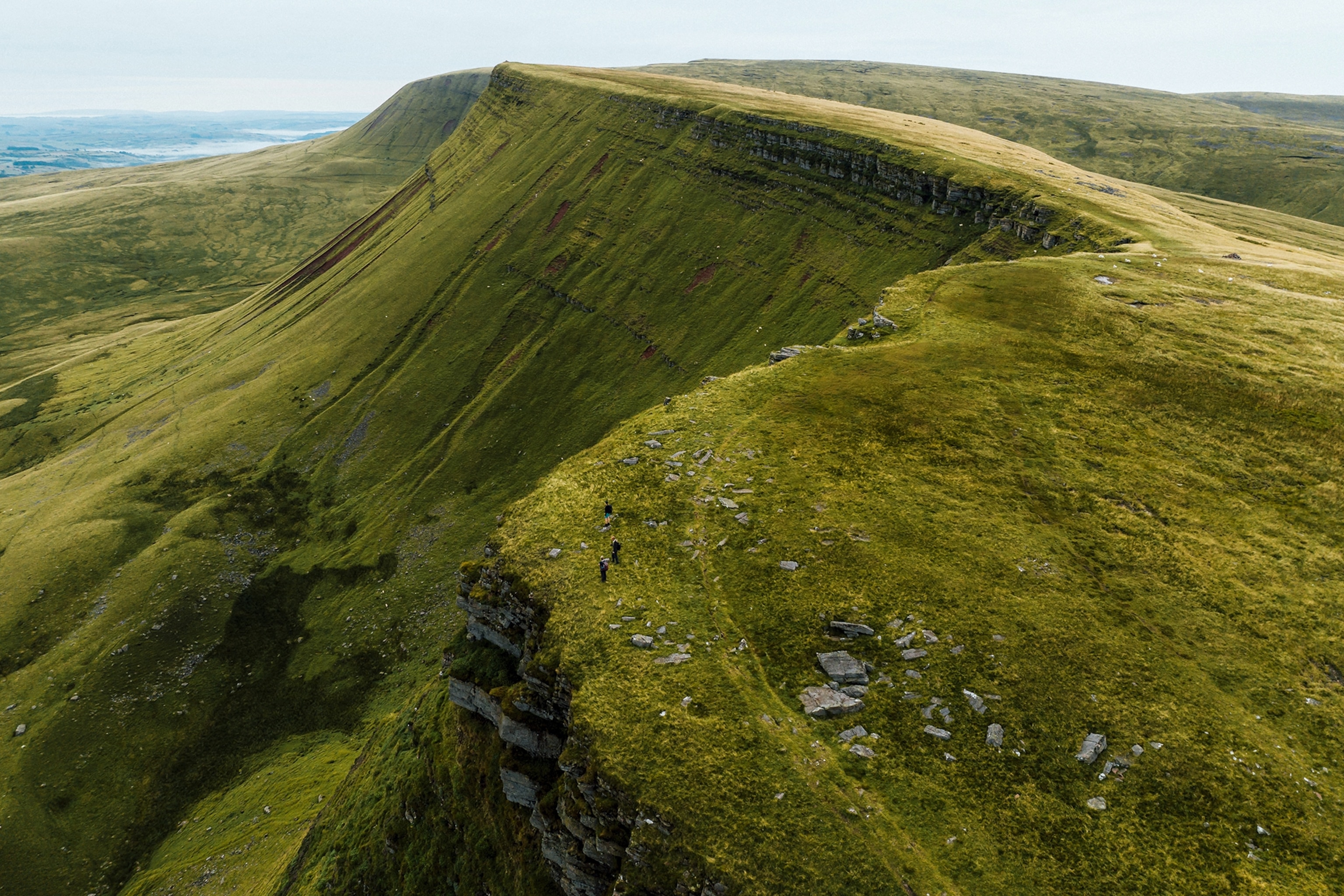 A wide landscape shot of a mountain passage with a path leading along the top.