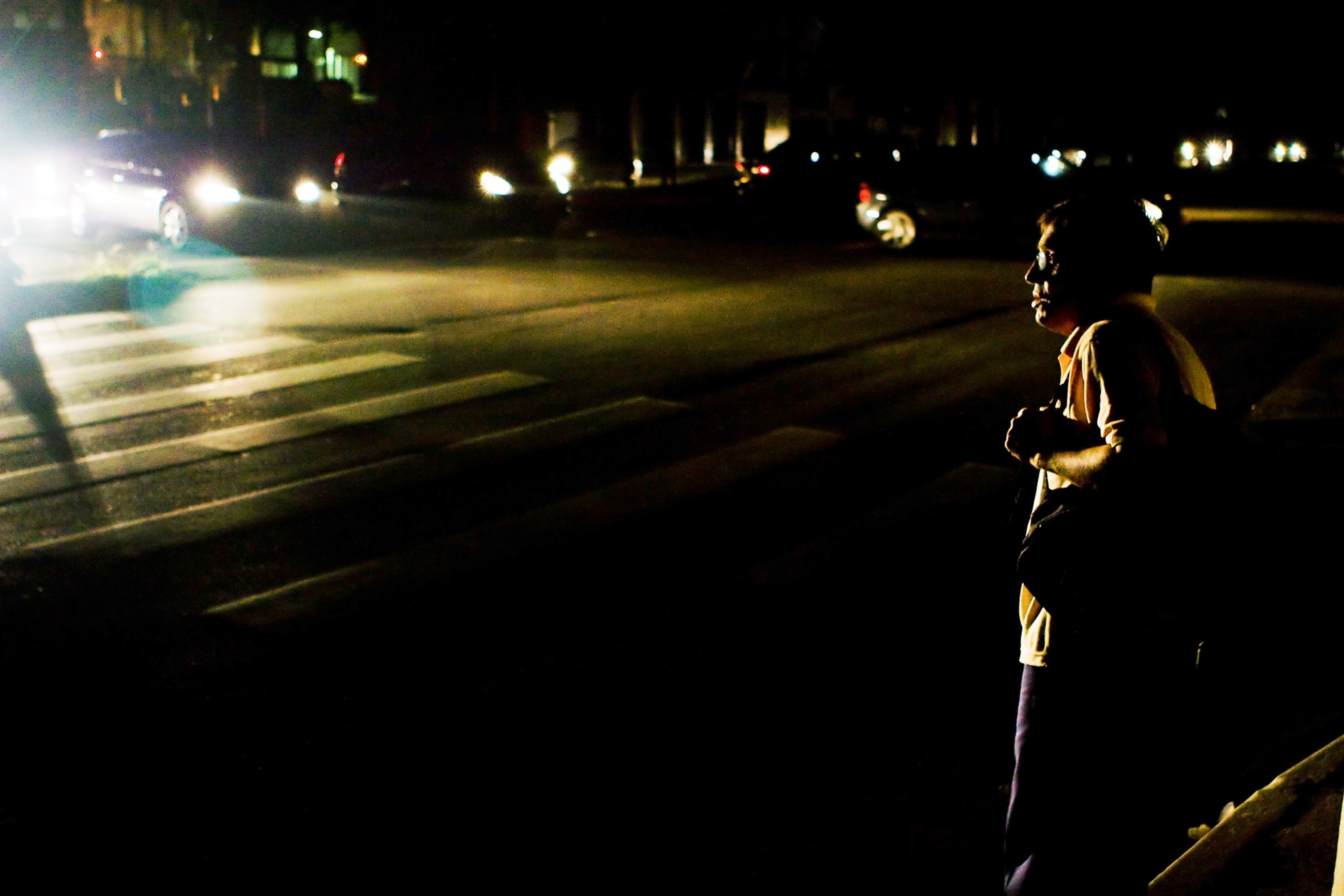 Blackout picture - a man waits to cross a street as vehicles pass during a huge blackout in São Paulo, Brazil, in 2009