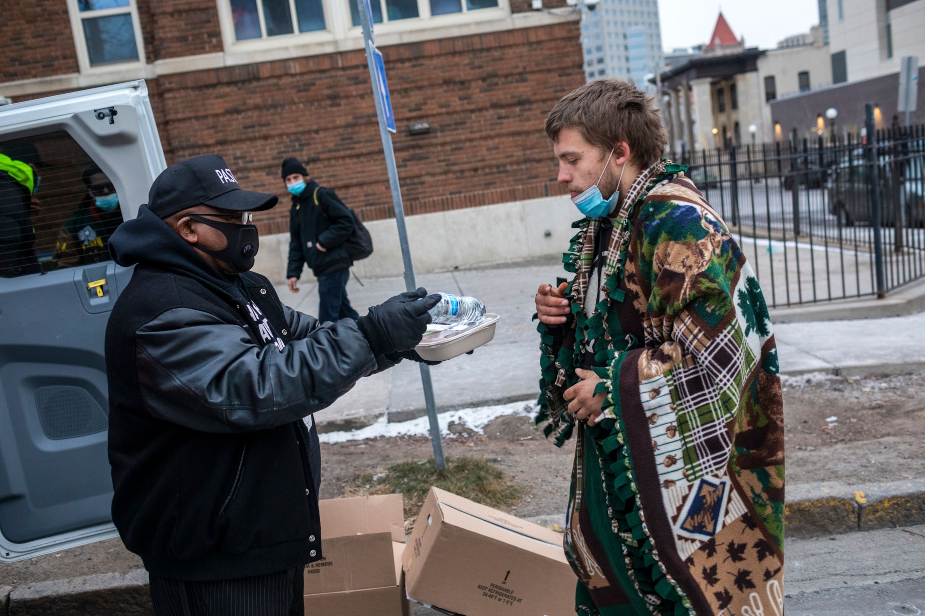 A Blanketed homeless man receives food on the street in St. Paul, Minnesota.