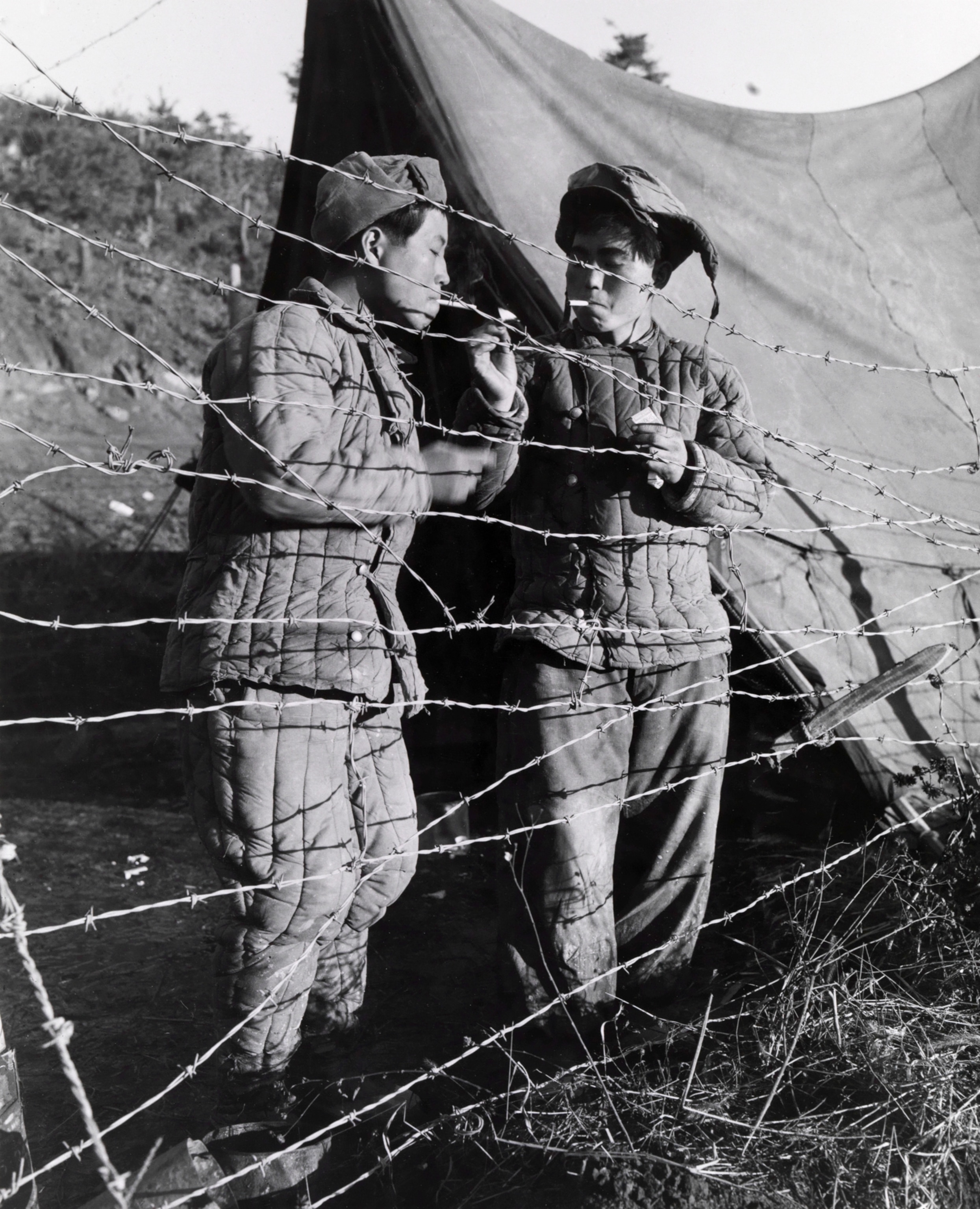 Two Korean prisoners of war enjoy a cigarette.