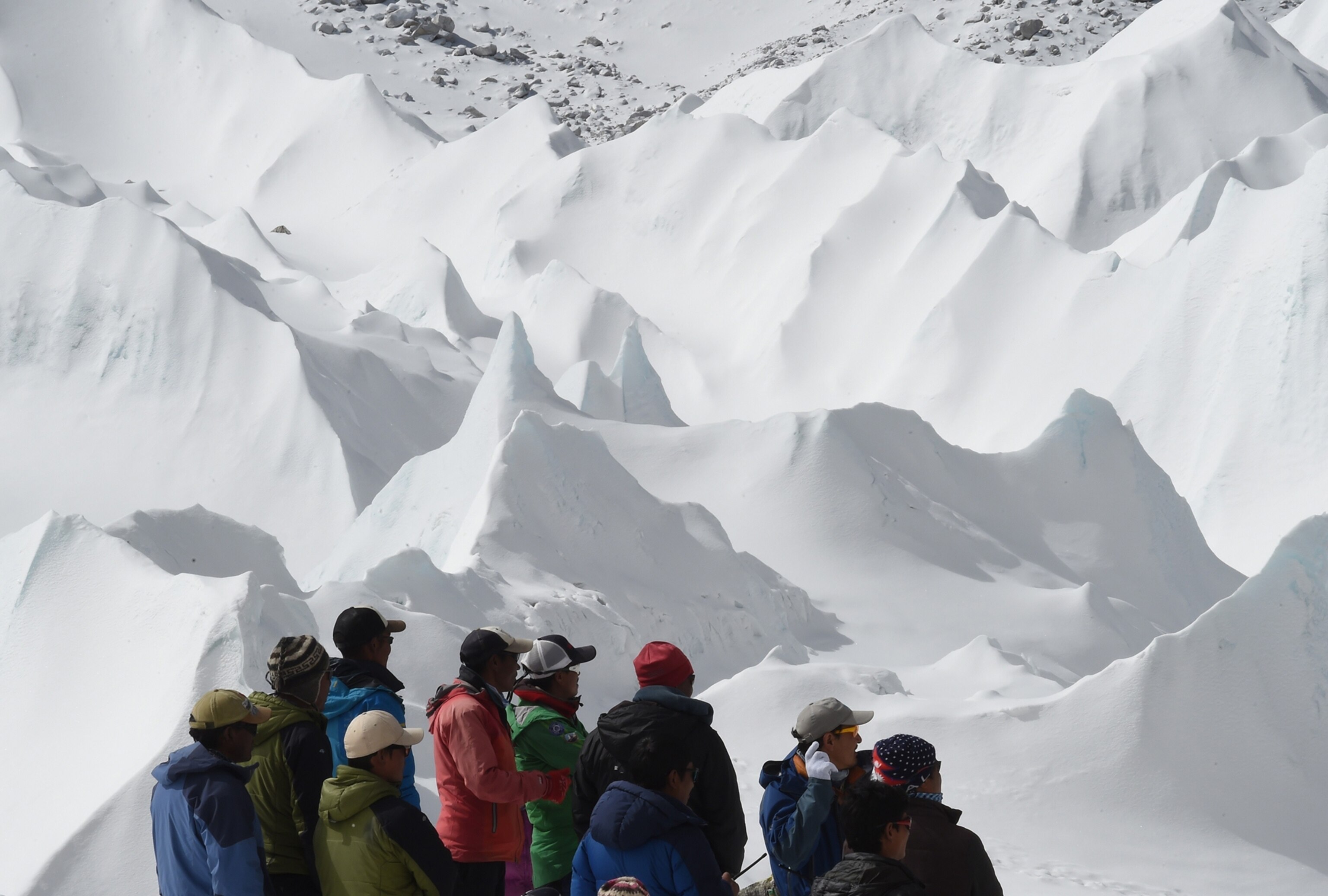 Nepali sherpas and other Nepali members of expeditions watch as a helicopter takes off