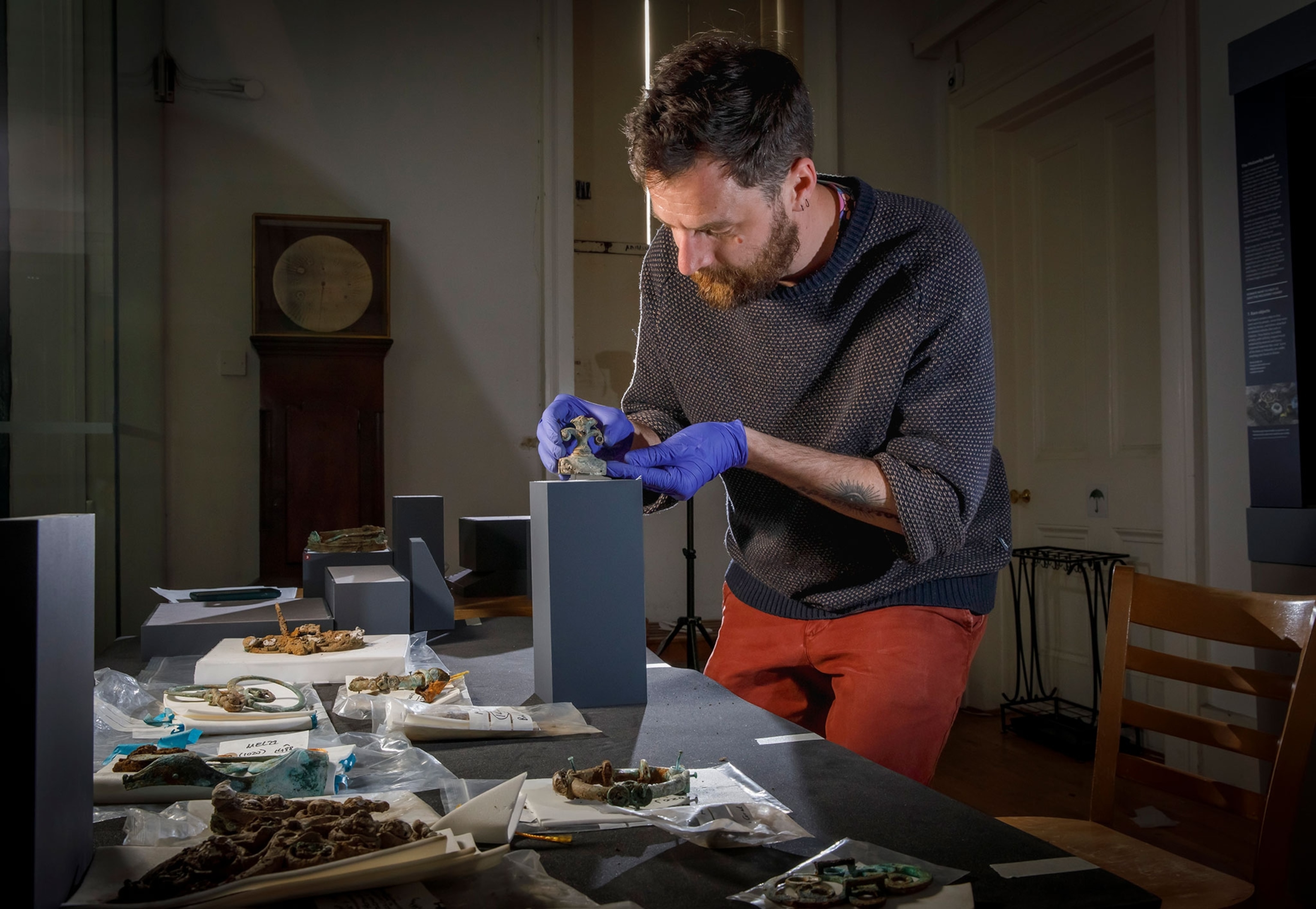 A man with pale skin and purple gloves working on objects.