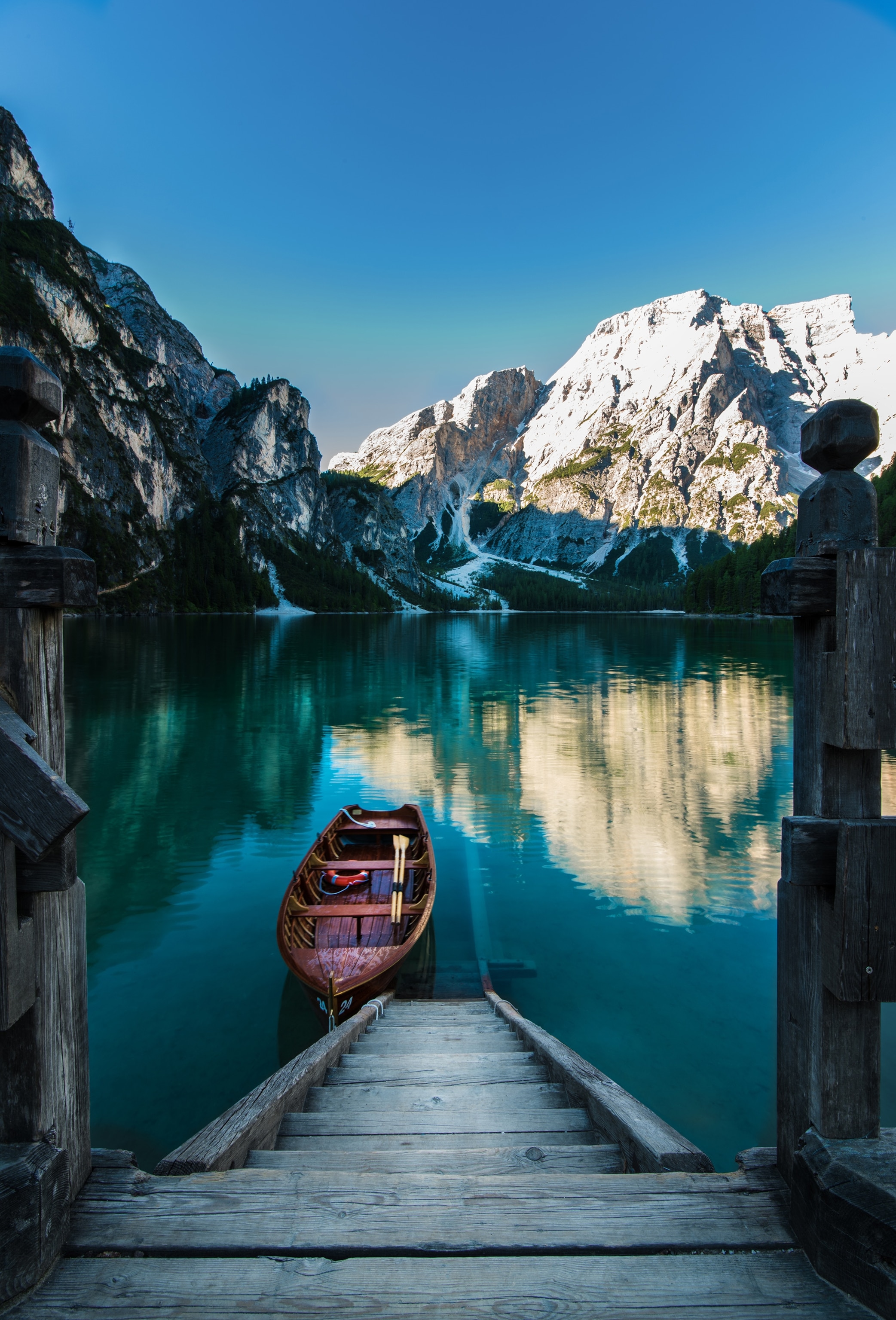 a row boat on a dock in Italy with snowcapped mountains in the background