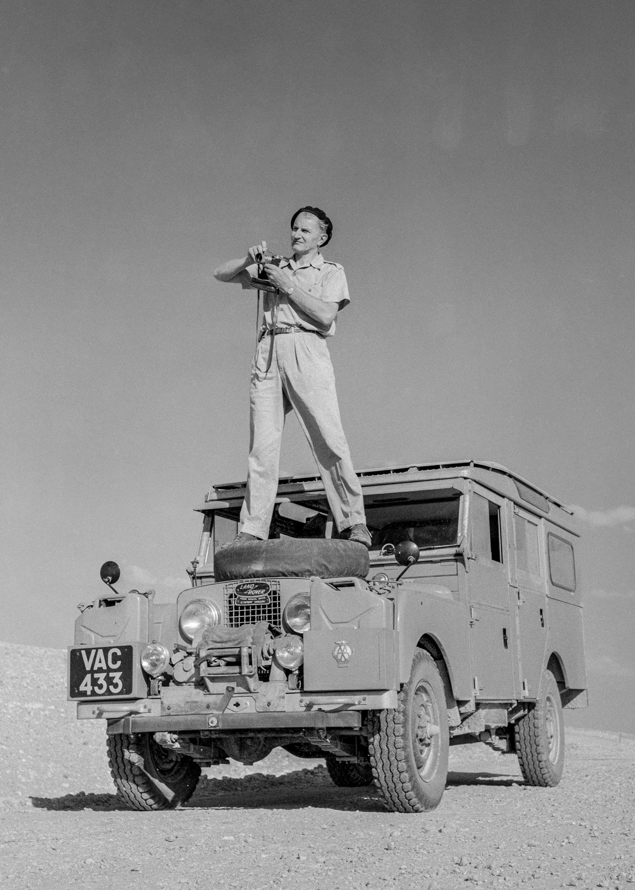 A man stands on top of his car.