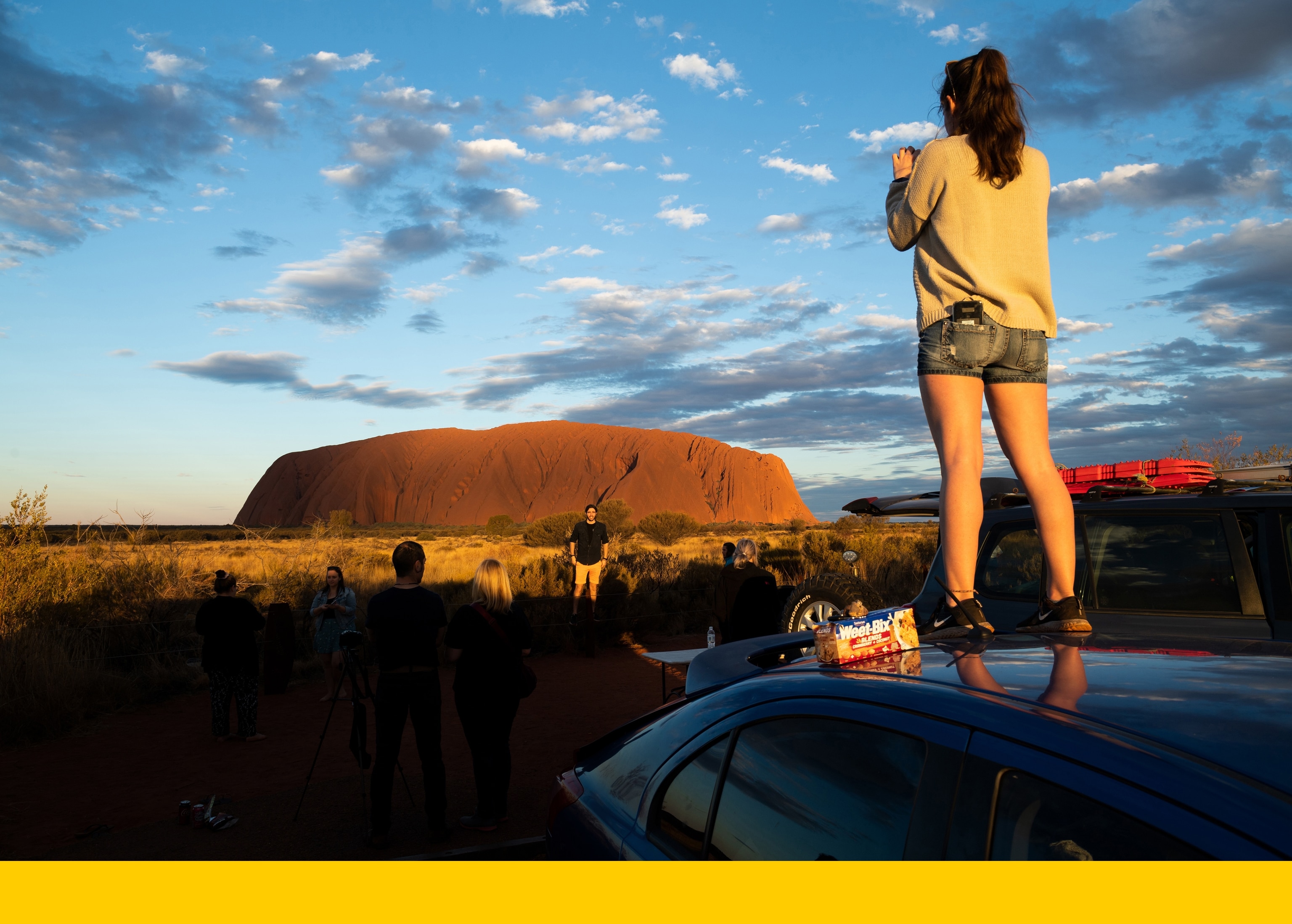 Tourist take photos of Uluru from the car sunset viewing area. 