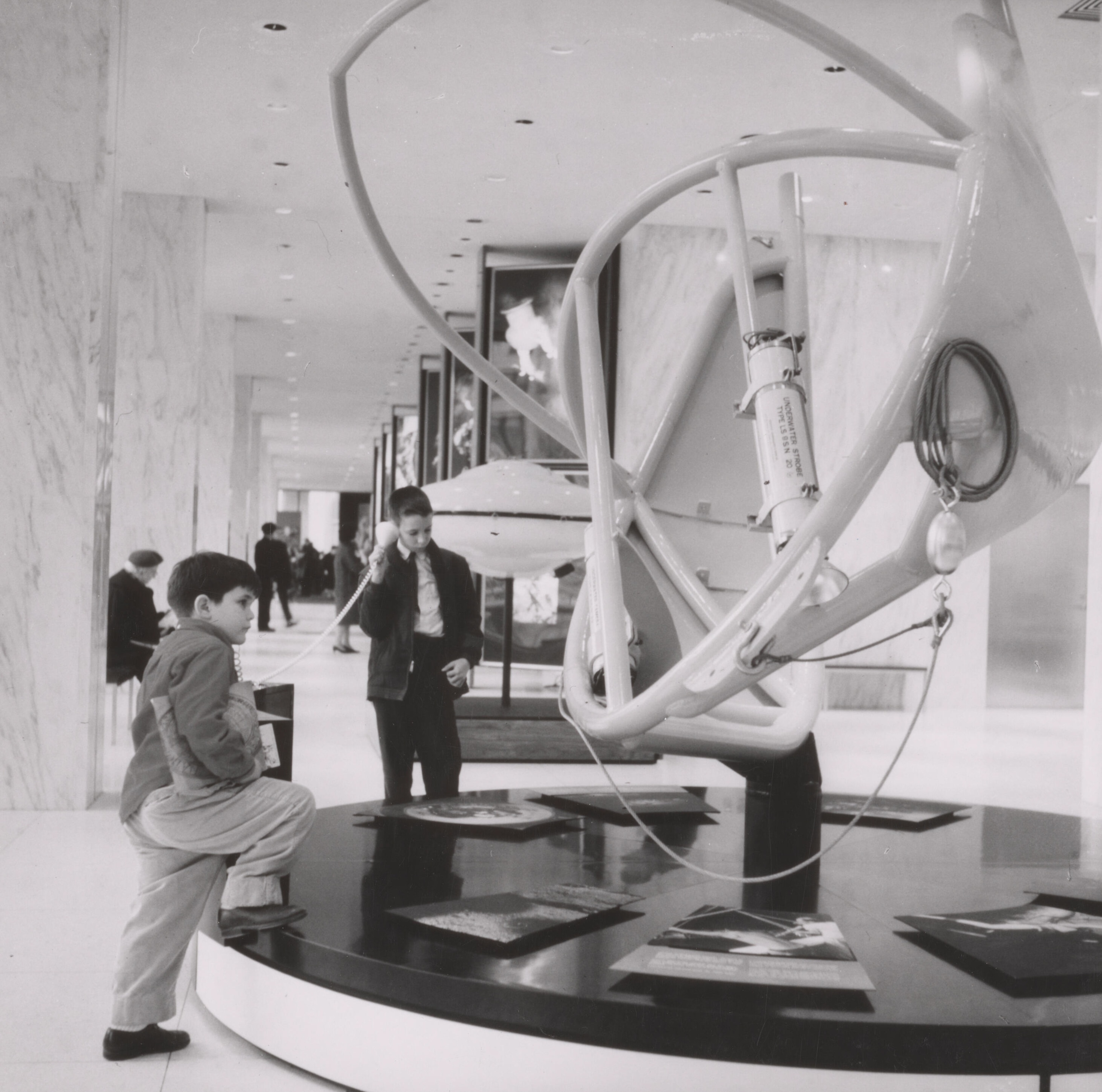 Two boys examining an underwater strobe on display at National Geographic Society headquarters.