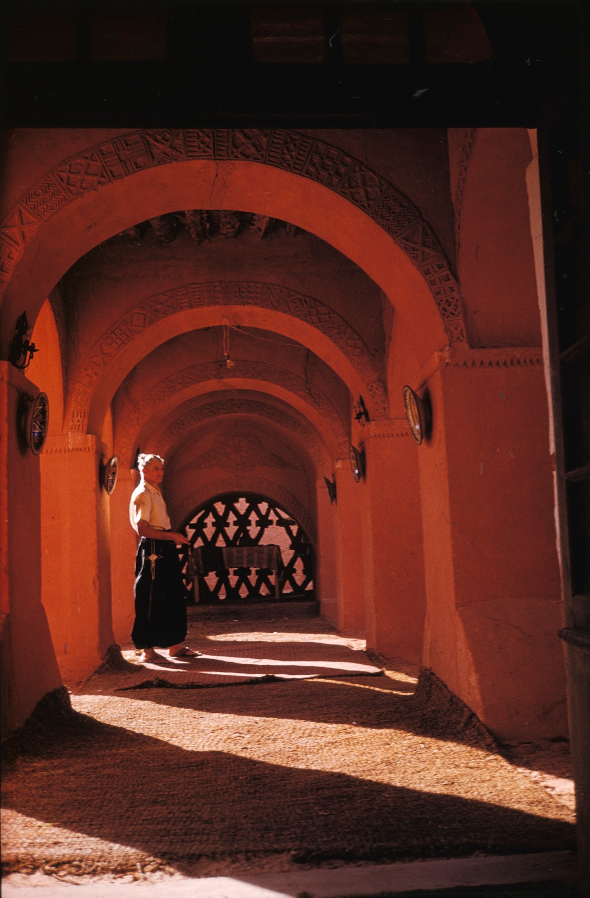 A man stands under red mud arches at a hotel