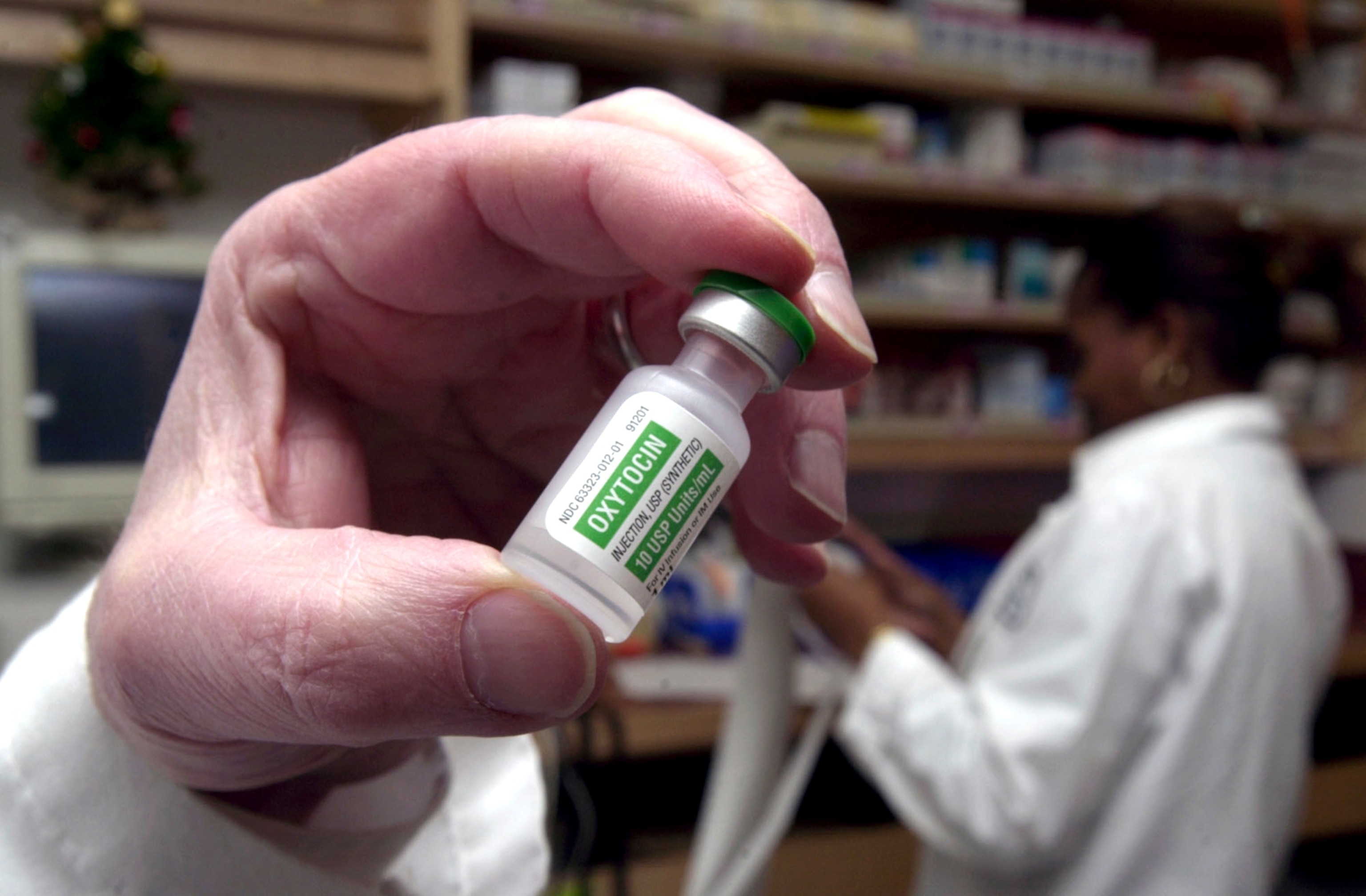 A pharmacist holds a vial of oxytocin.
