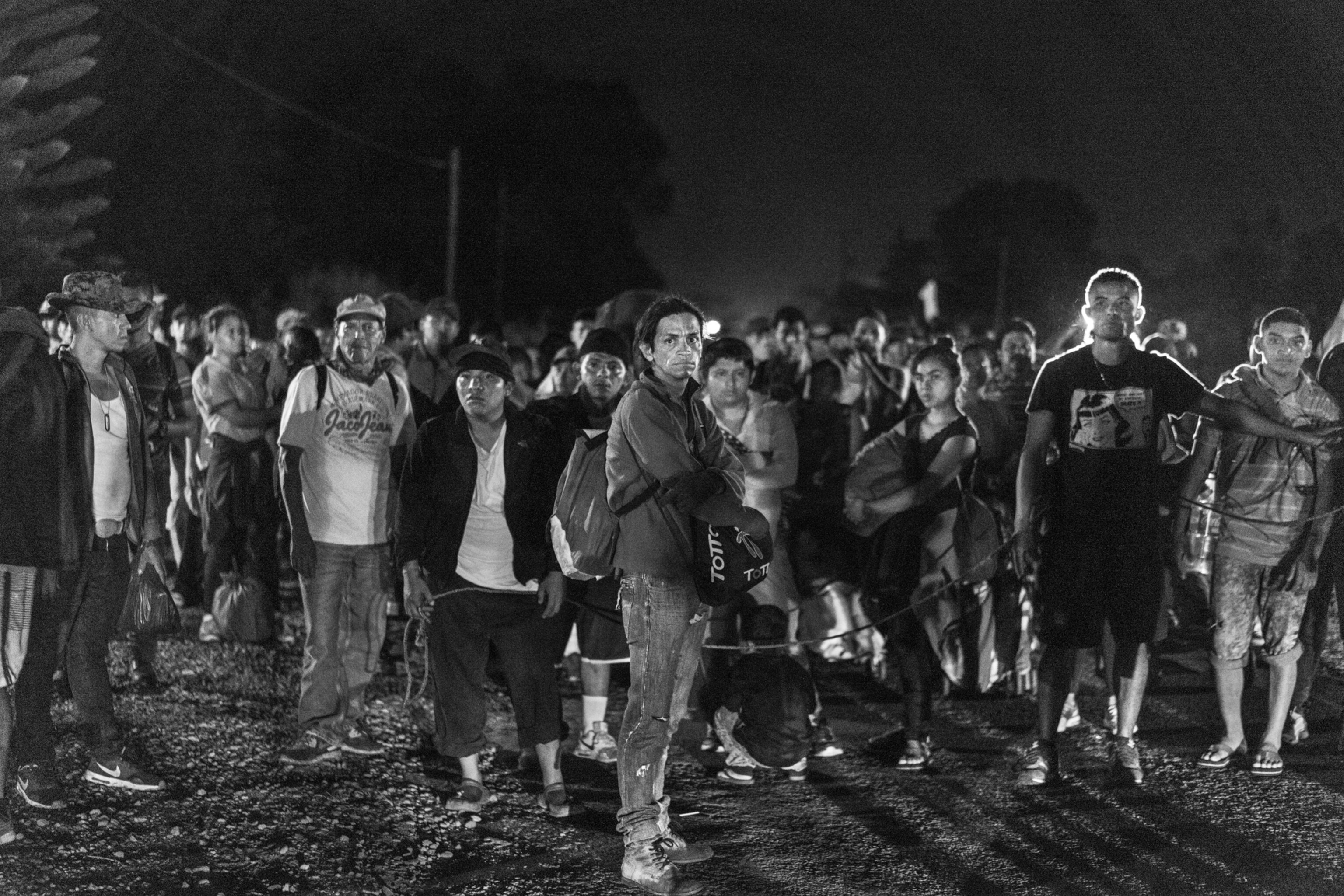 men outside at night standing and waiting on gravel