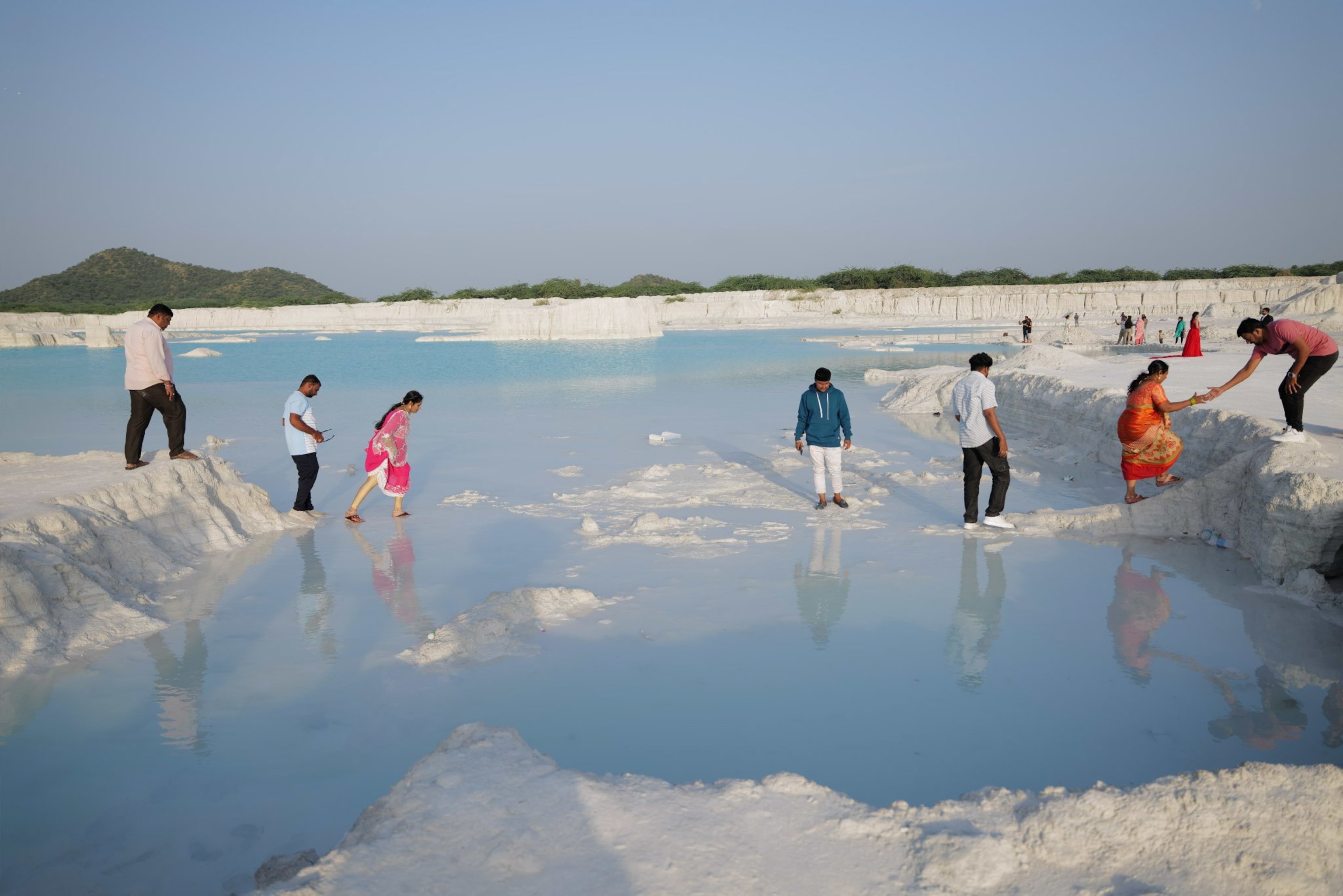 A group of people cross the marble dumping yard in a straight line.